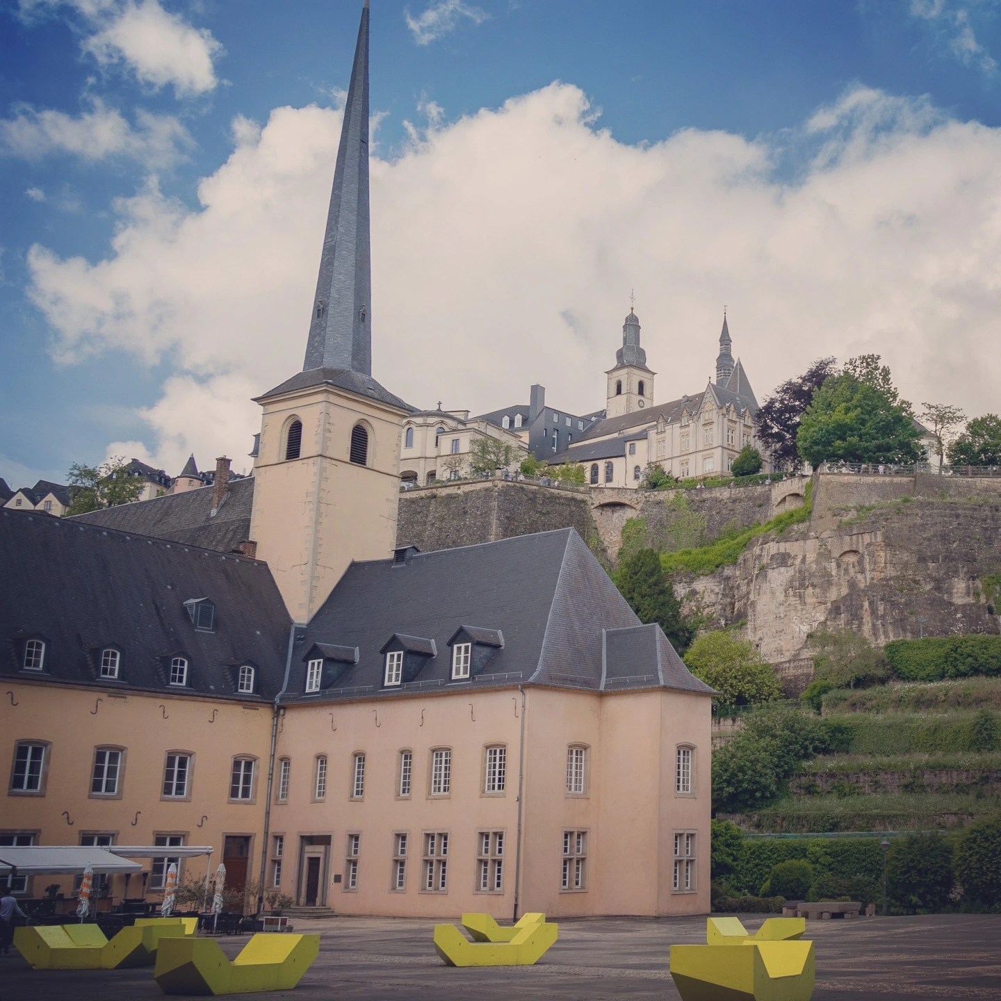 Neumünster Abbey courtyard with yellow modern seating installations in Luxembourg City.