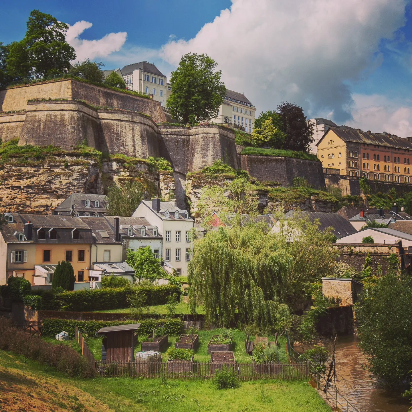 Small gardens and pastel houses beneath Luxembourg’s massive fortress walls.