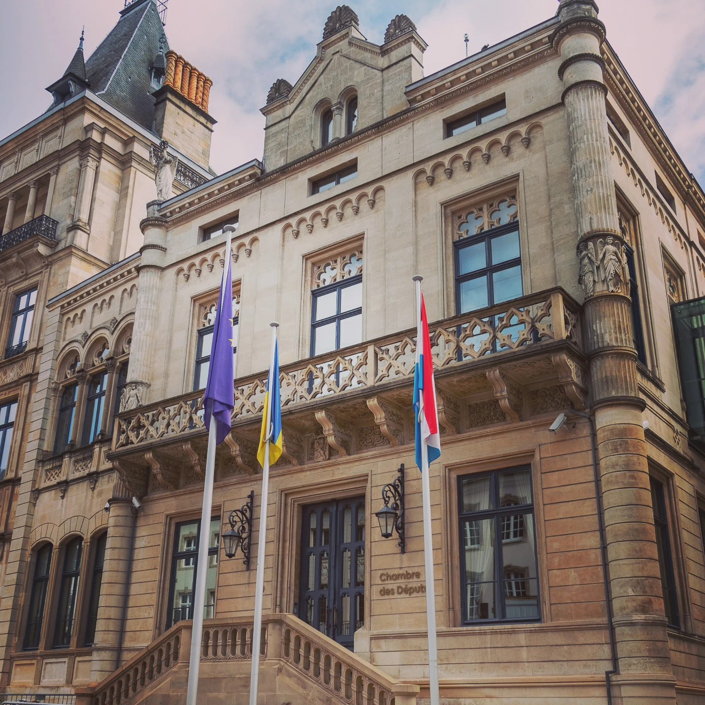 Facade of Luxembourg’s Chamber of Deputies with flags in front.