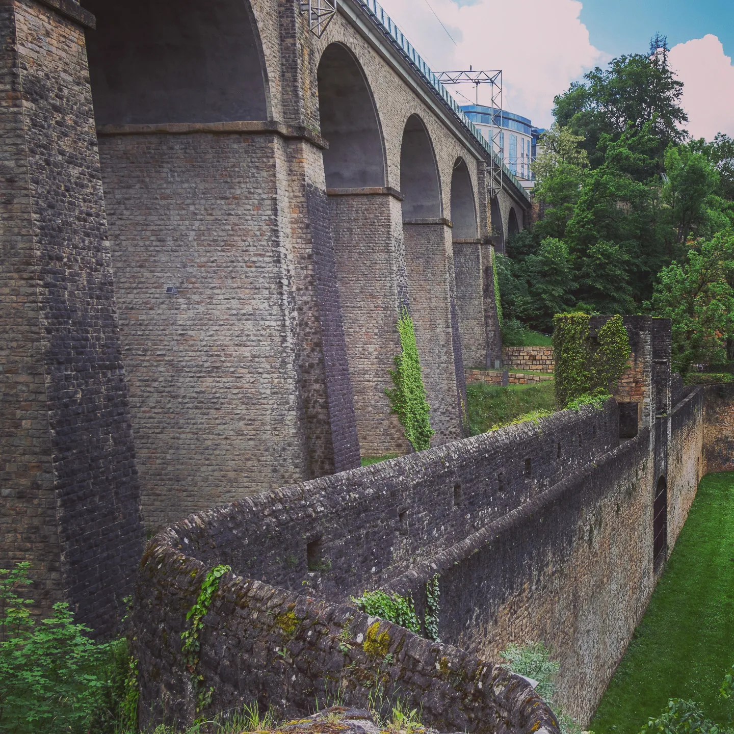 Stone viaduct and fortified wall covered with ivy in Luxembourg City.