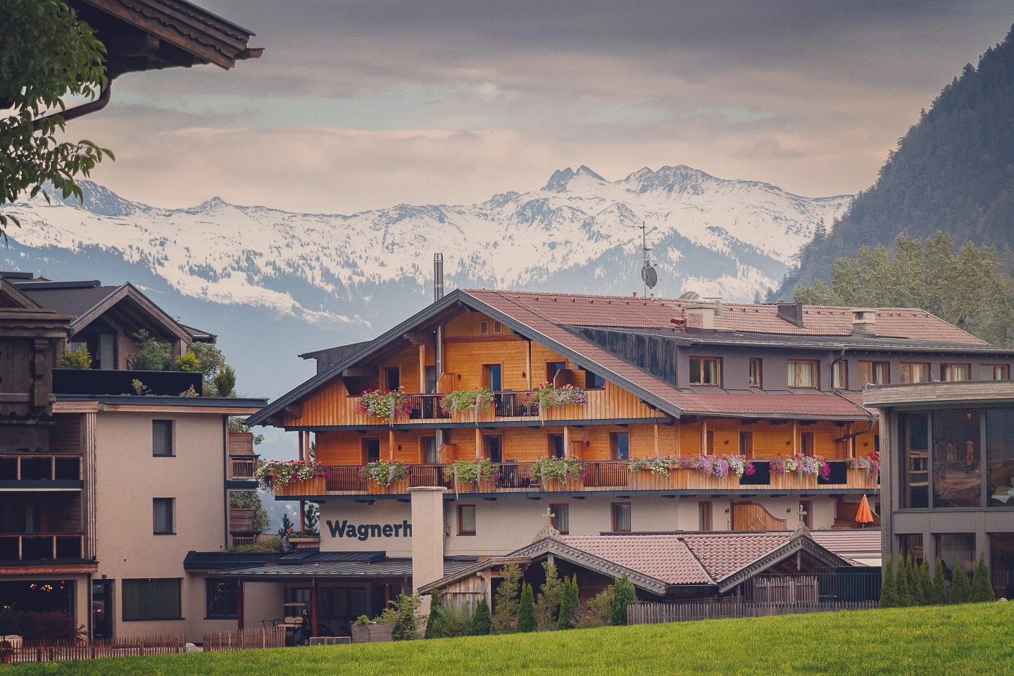 Flower-decked Wagnerhof chalet in Pertisau with snowy mountains in the distance.