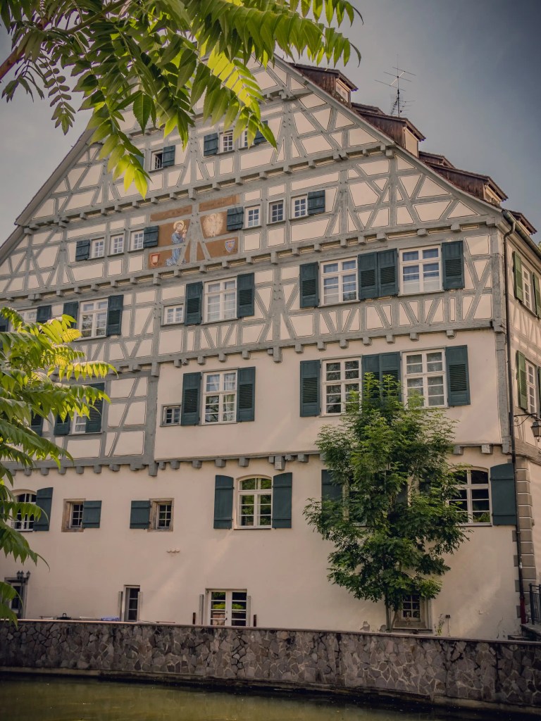 A large half-timbered building in Horb am Neckar with green shutters and decorative paintings on its facade.