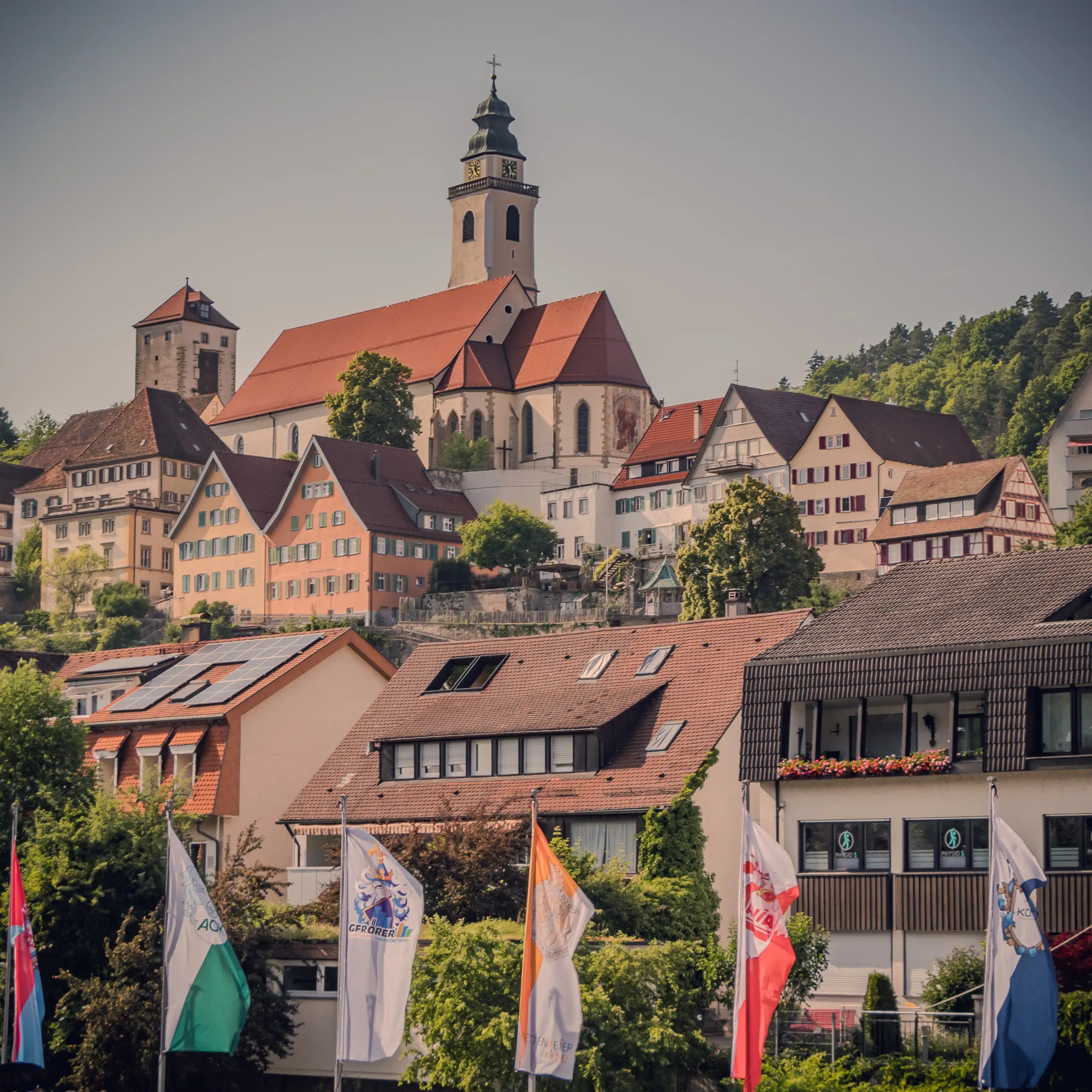 Elevated view of Horb’s town center with flags in the foreground and the church and historic tower above.