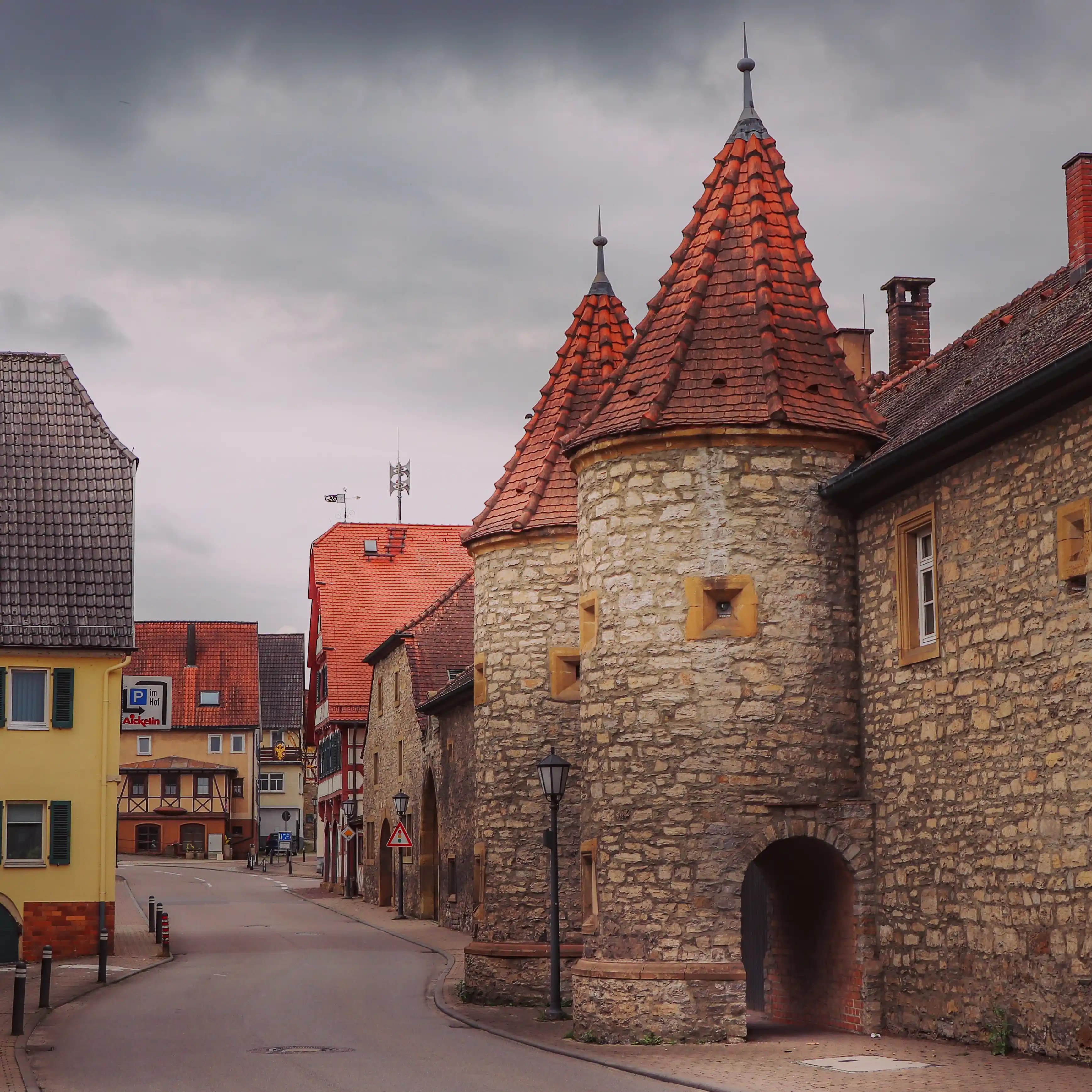 Cobblestone street in Bad Friedrichshall flanked by medieval towers and old town buildings.