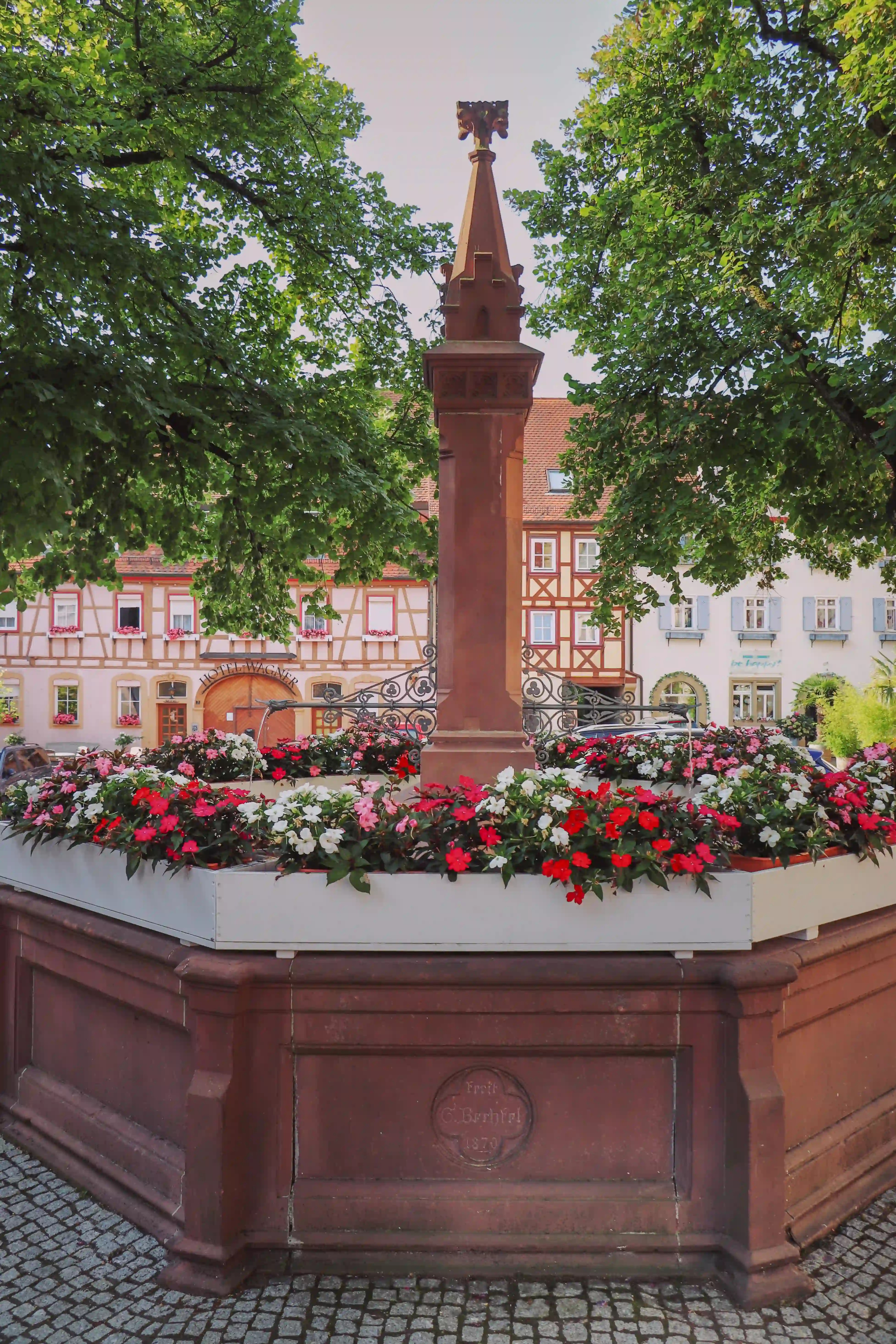 Octagonal red-sandstone market fountain with flower boxes and slender obelisk, Bad Wimpfen.