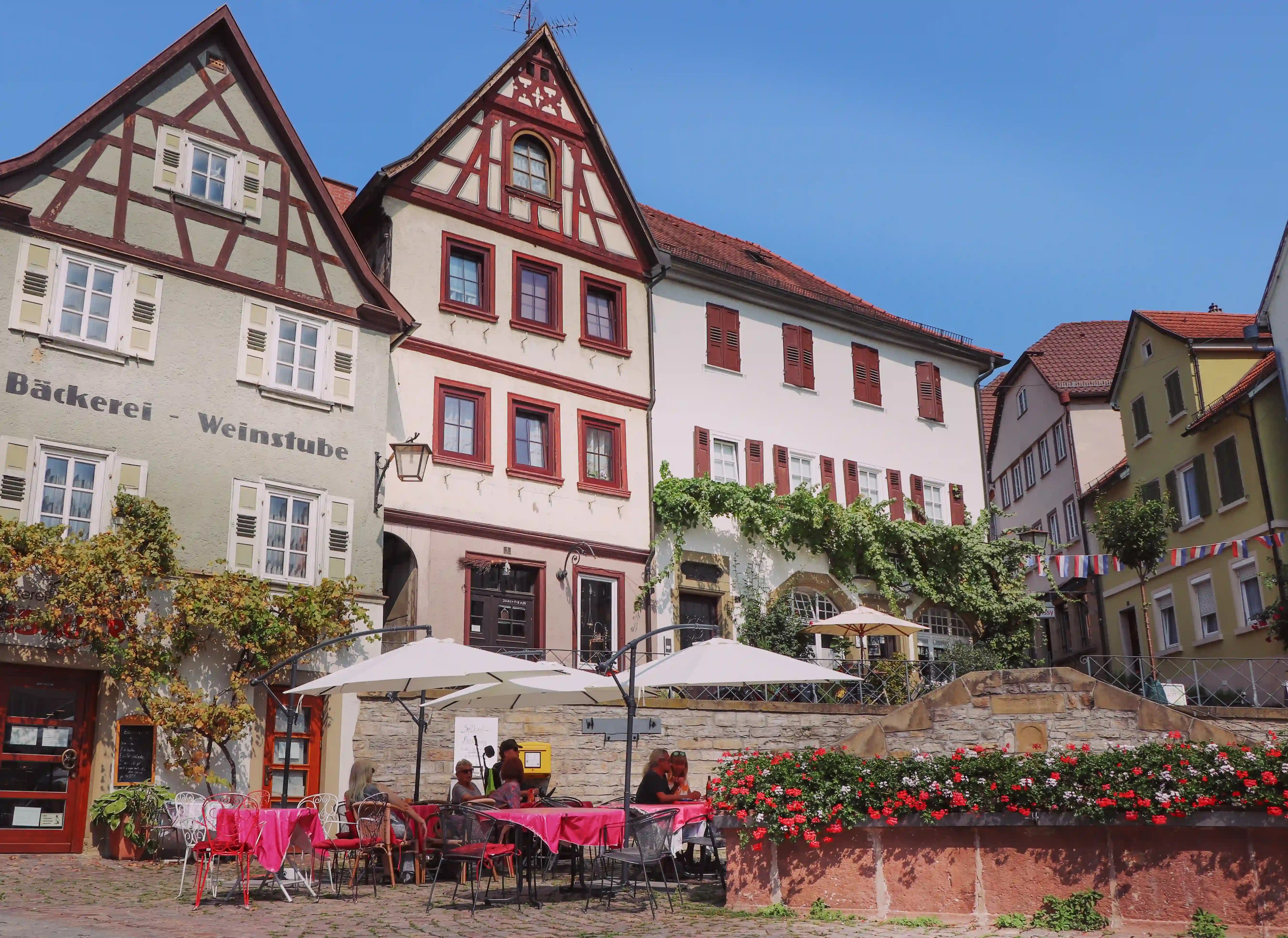 Market square cafés with umbrellas and historic façades—Bäckerei & Weinstube—Bad Wimpfen.