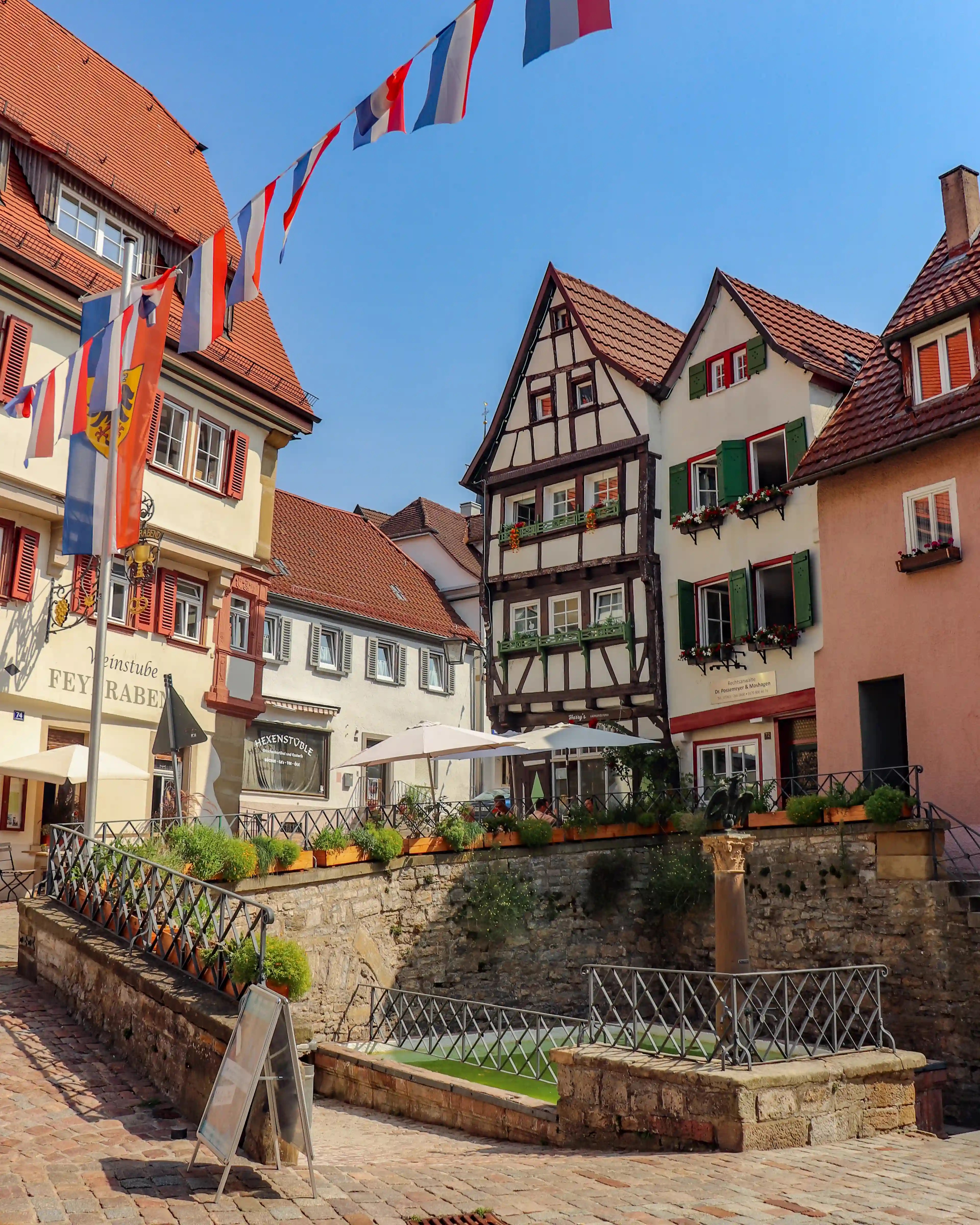 Bunting over half-timbered houses and a sunken fountain in Bad Wimpfen’s old town.