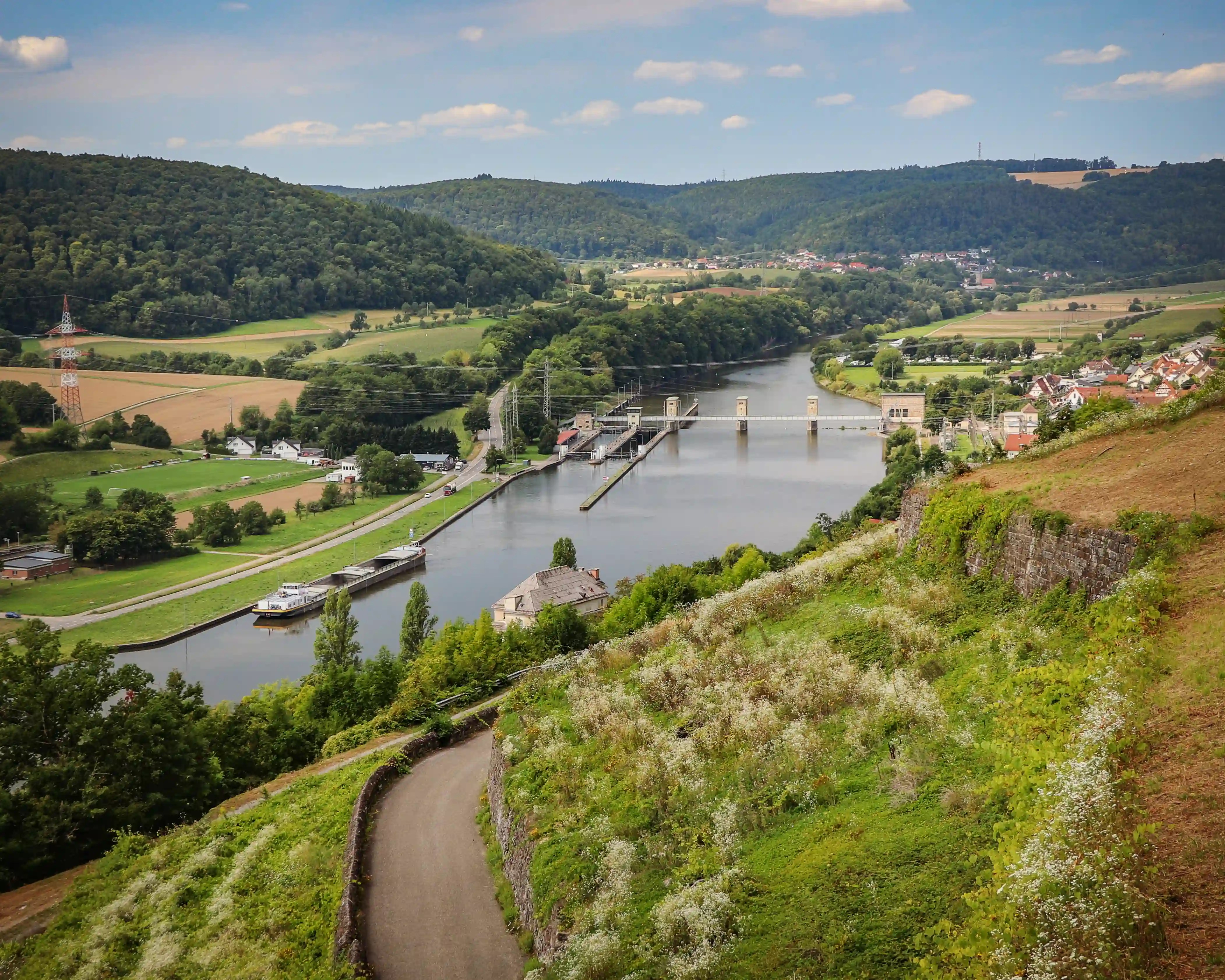 Neckar River and locks seen from above with boats, fields, and rolling hills.