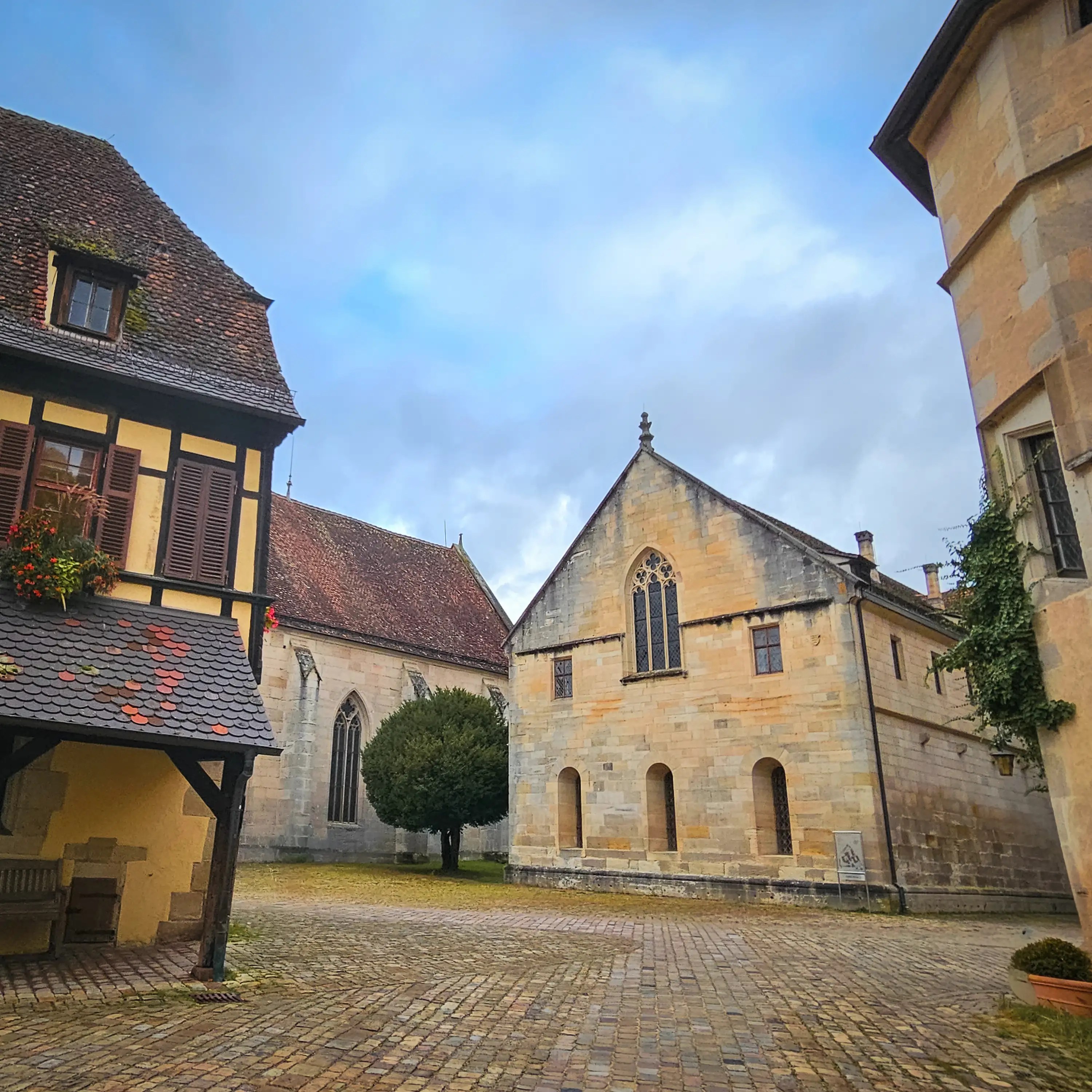 Courtyard view with half-timbered building and Gothic chapel at Bebenhausen Monastery.