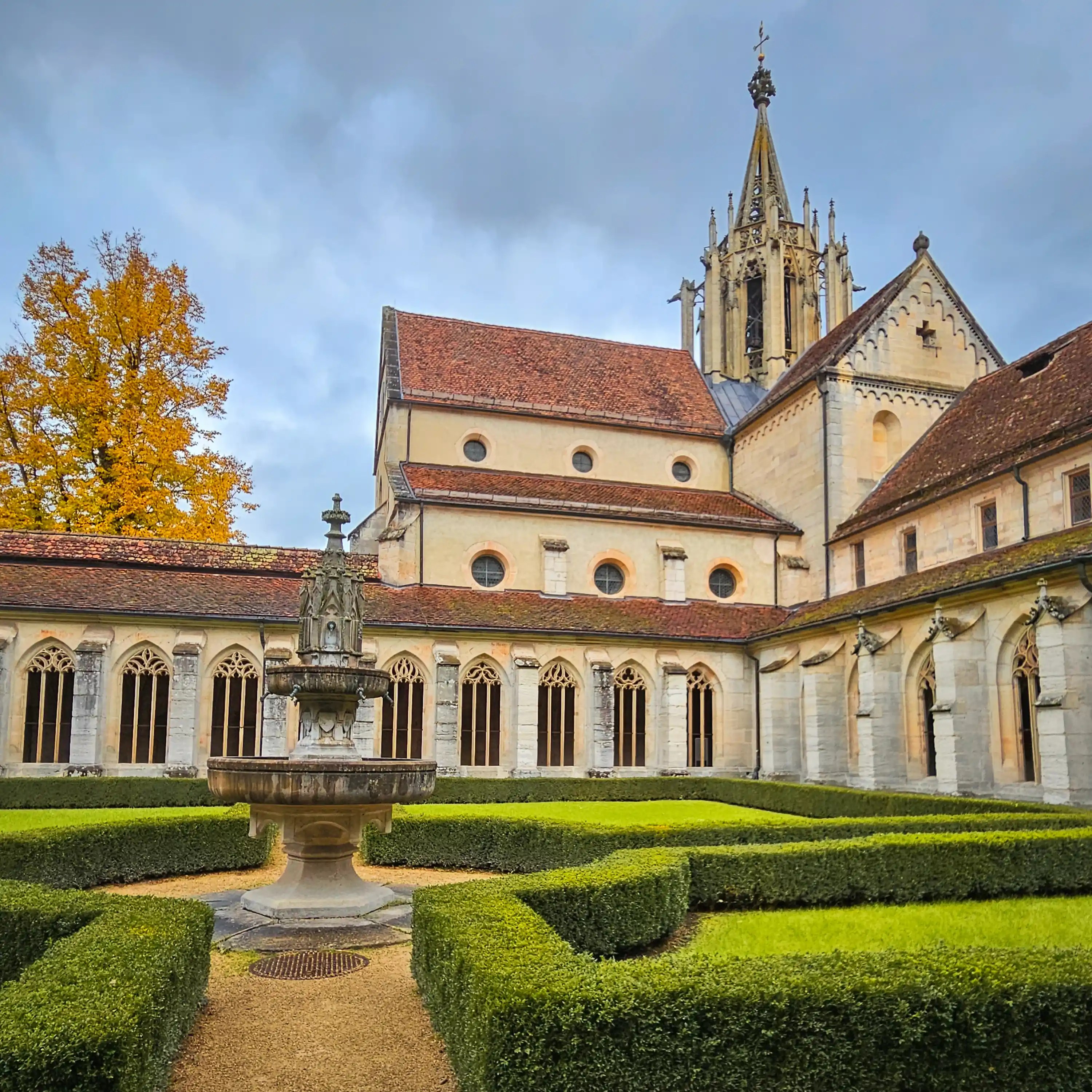 Fountain at the center of the cloister courtyard at Bebenhausen with trimmed hedges.