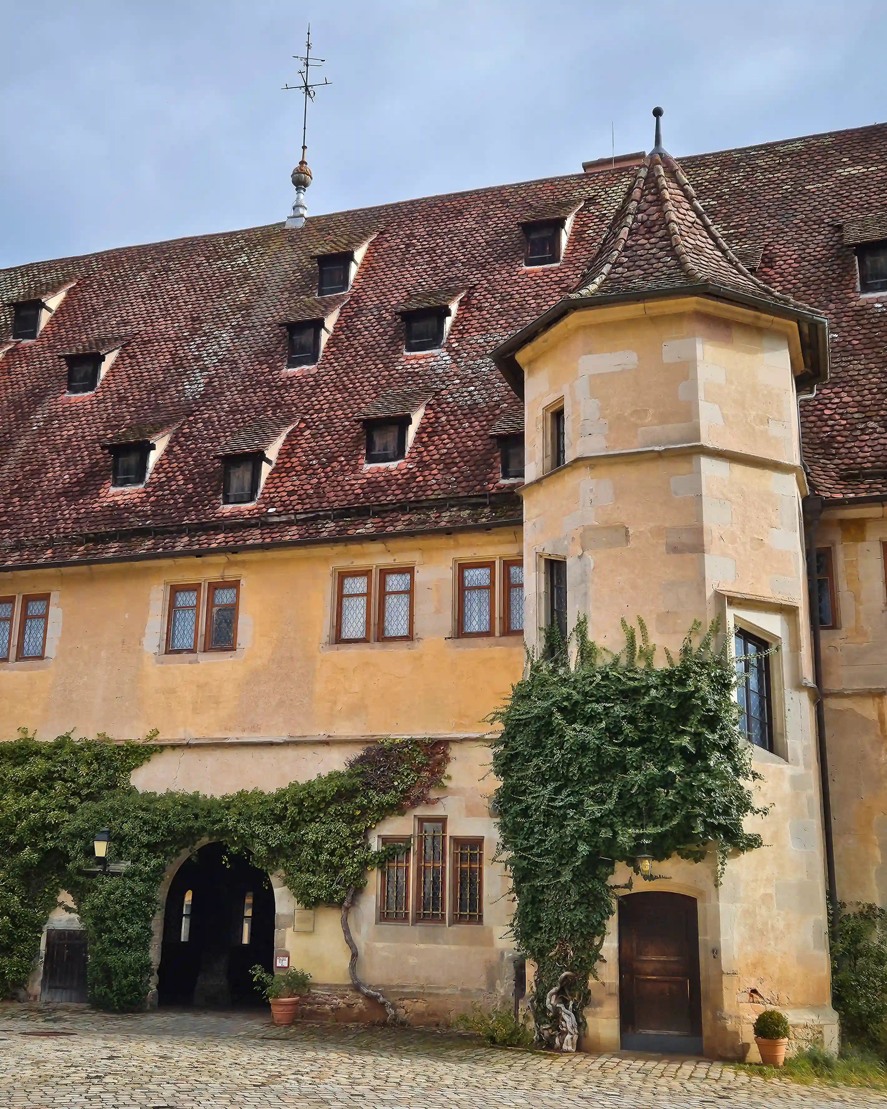 Yellow monastery building with small tower and ivy at Bebenhausen.