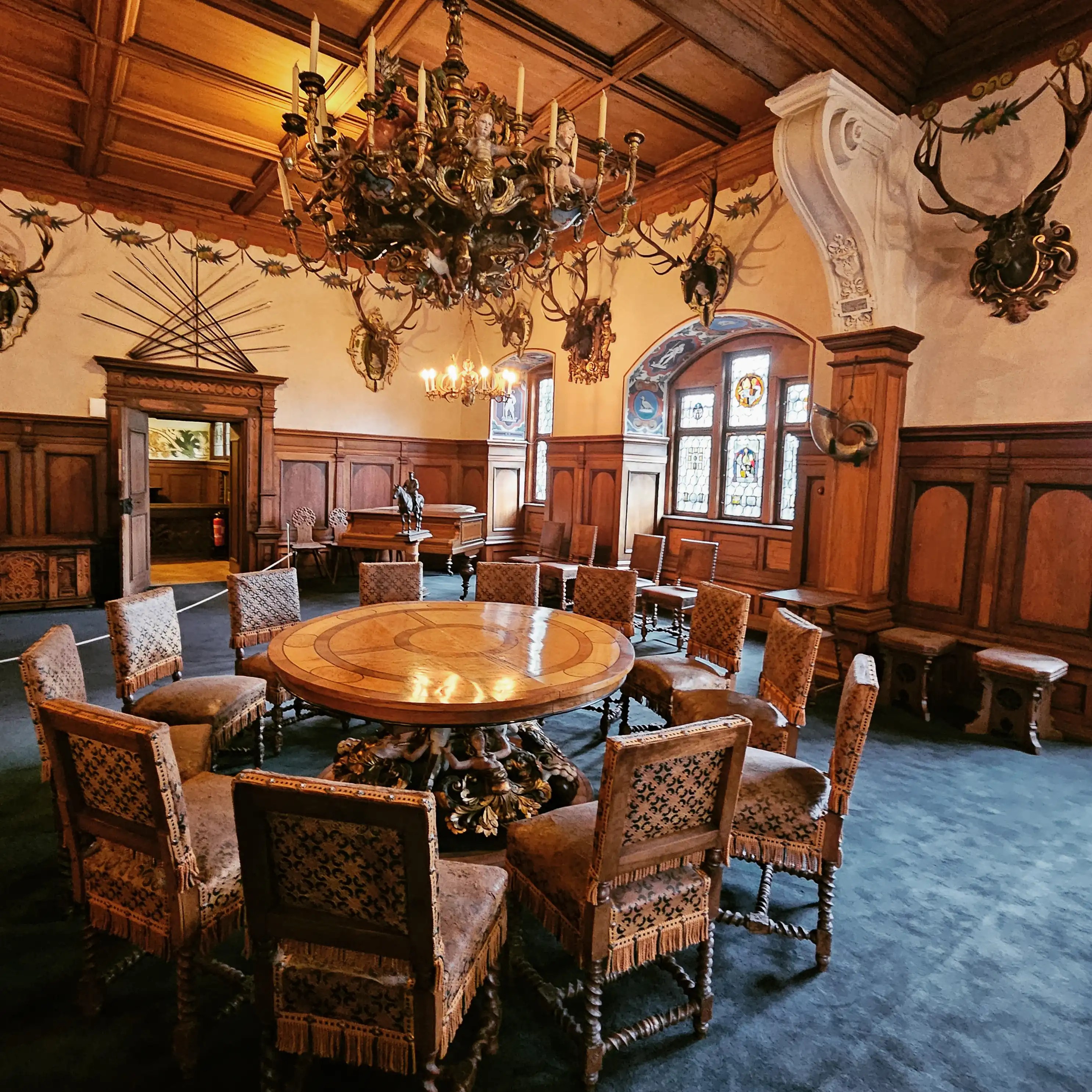 Hunting room with round table, antler mounts, and ornate chandelier at Bebenhausen.