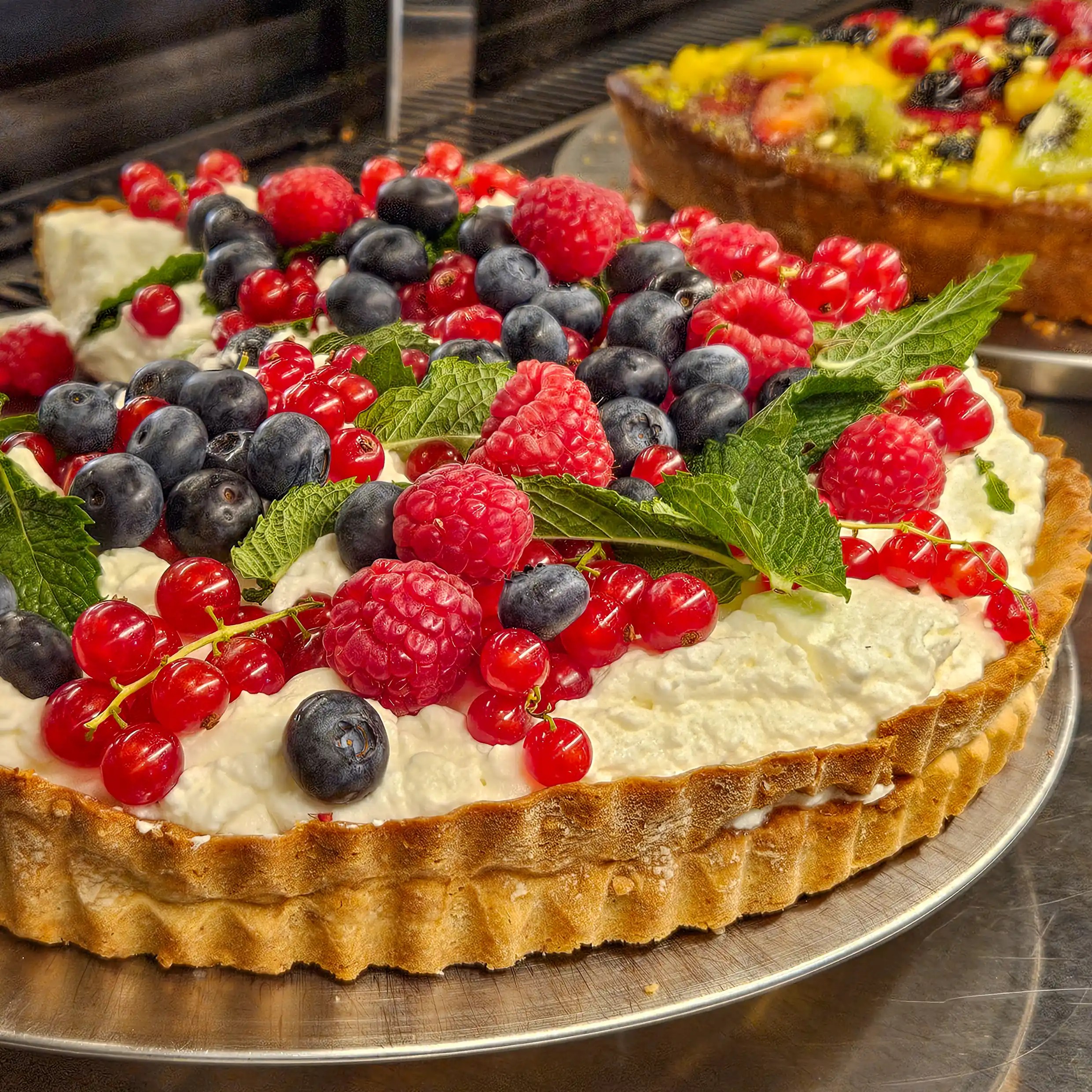 Fresh berry tart topped with raspberries, blueberries, currants, and mint leaves at Café im Kloster.