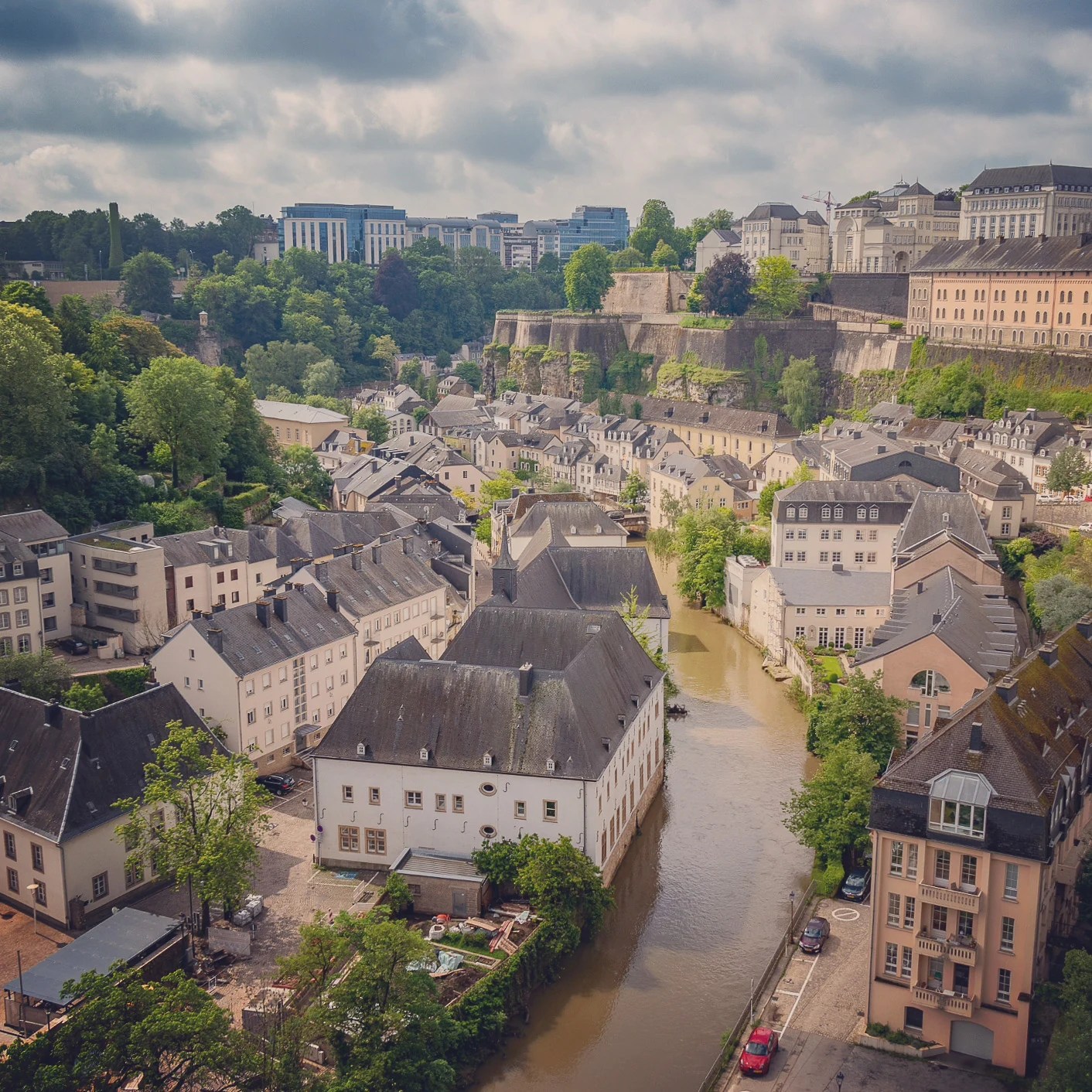 Aerial view of Luxembourg’s Grund with houses, river, and fortress walls.