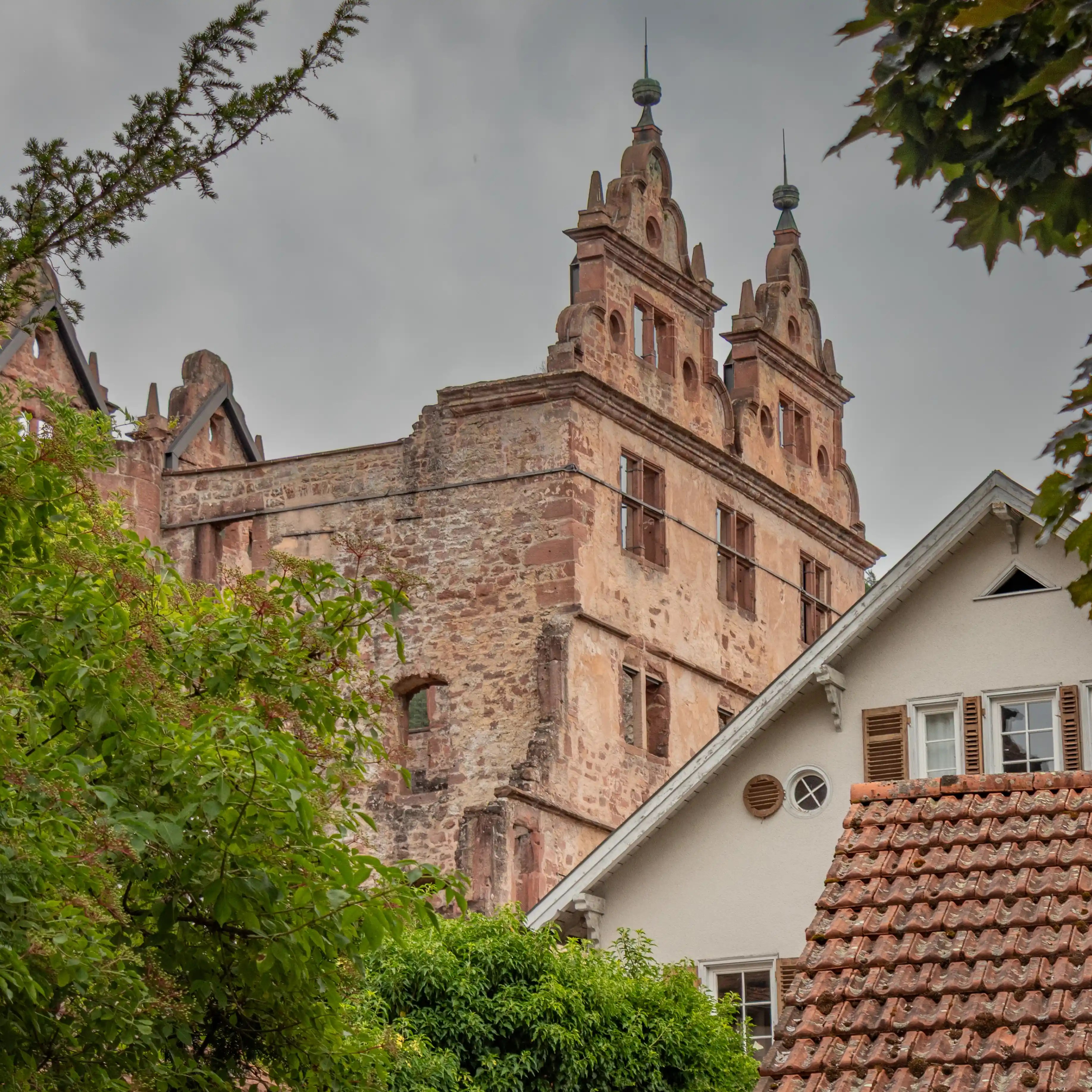 Ruins of Hirsau Monastery’s Hunting Lodge rising above nearby houses with tiled roofs.