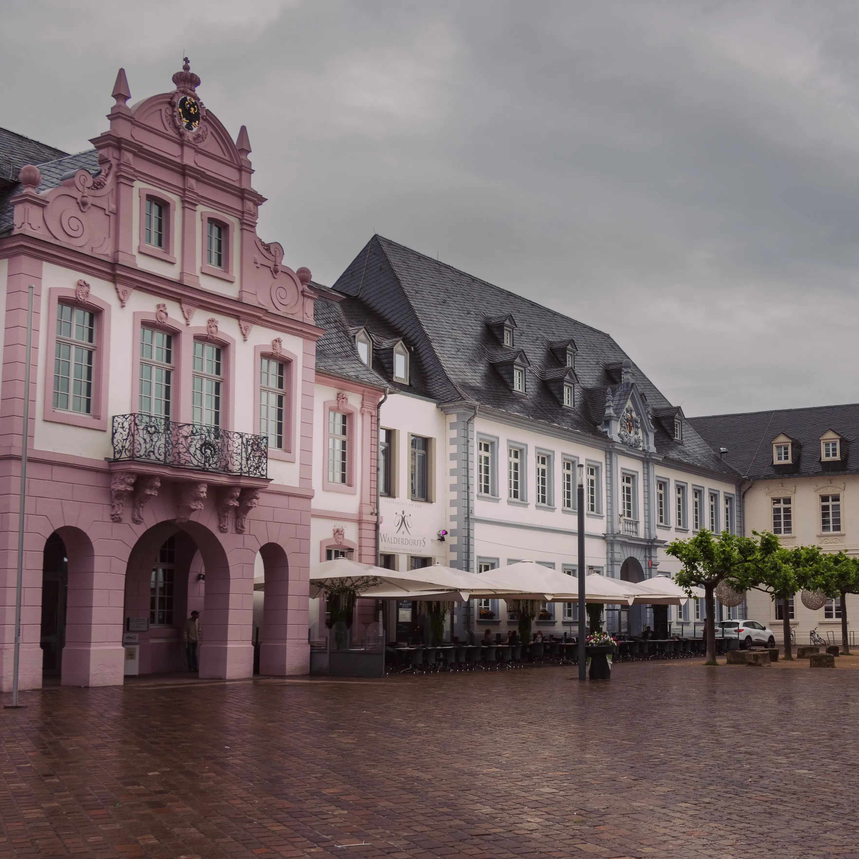 Elegant pastel-pink and white baroque-style buildings with arched windows in Trier.
