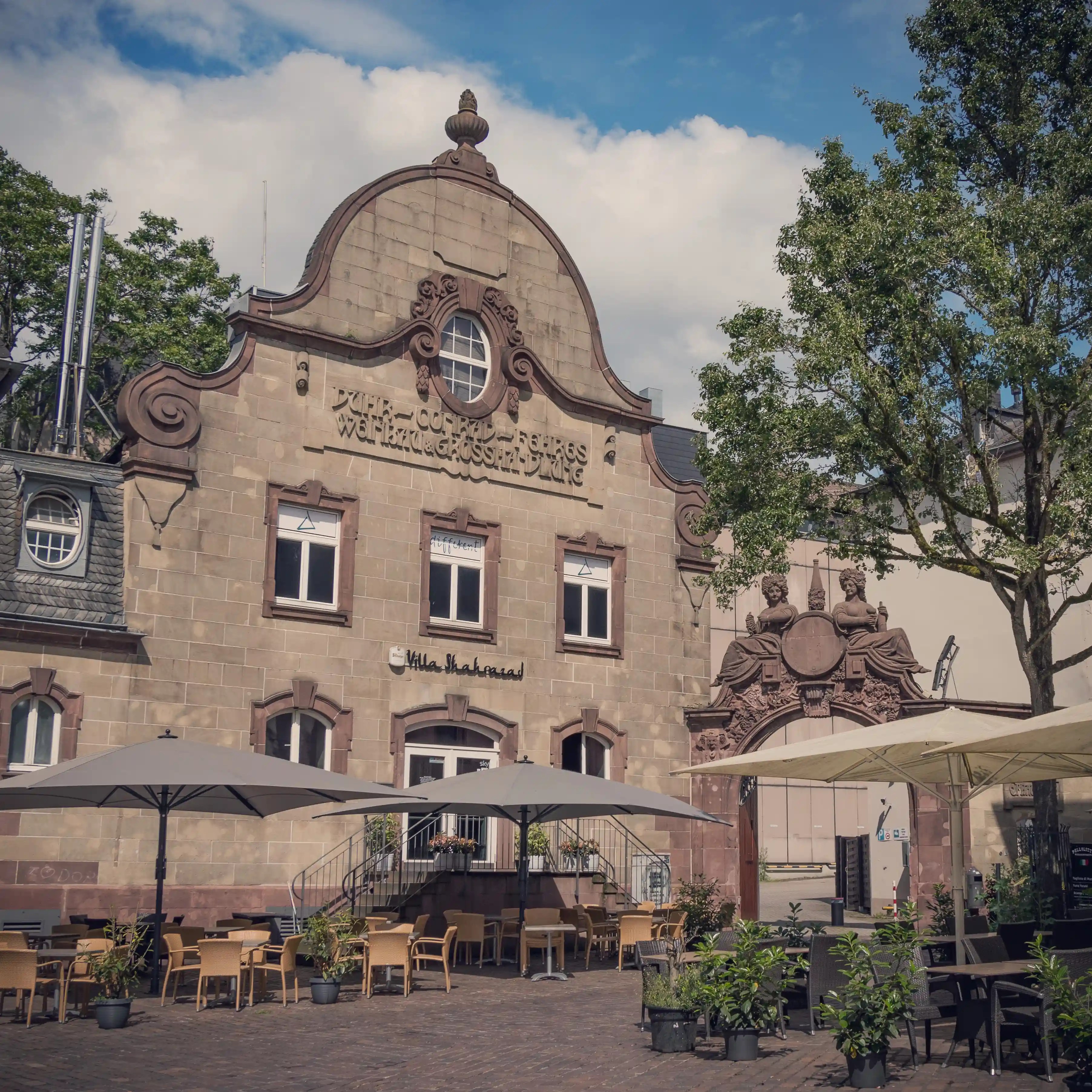 Historic stone building with ornate gable and outdoor seating in Trier, Germany.