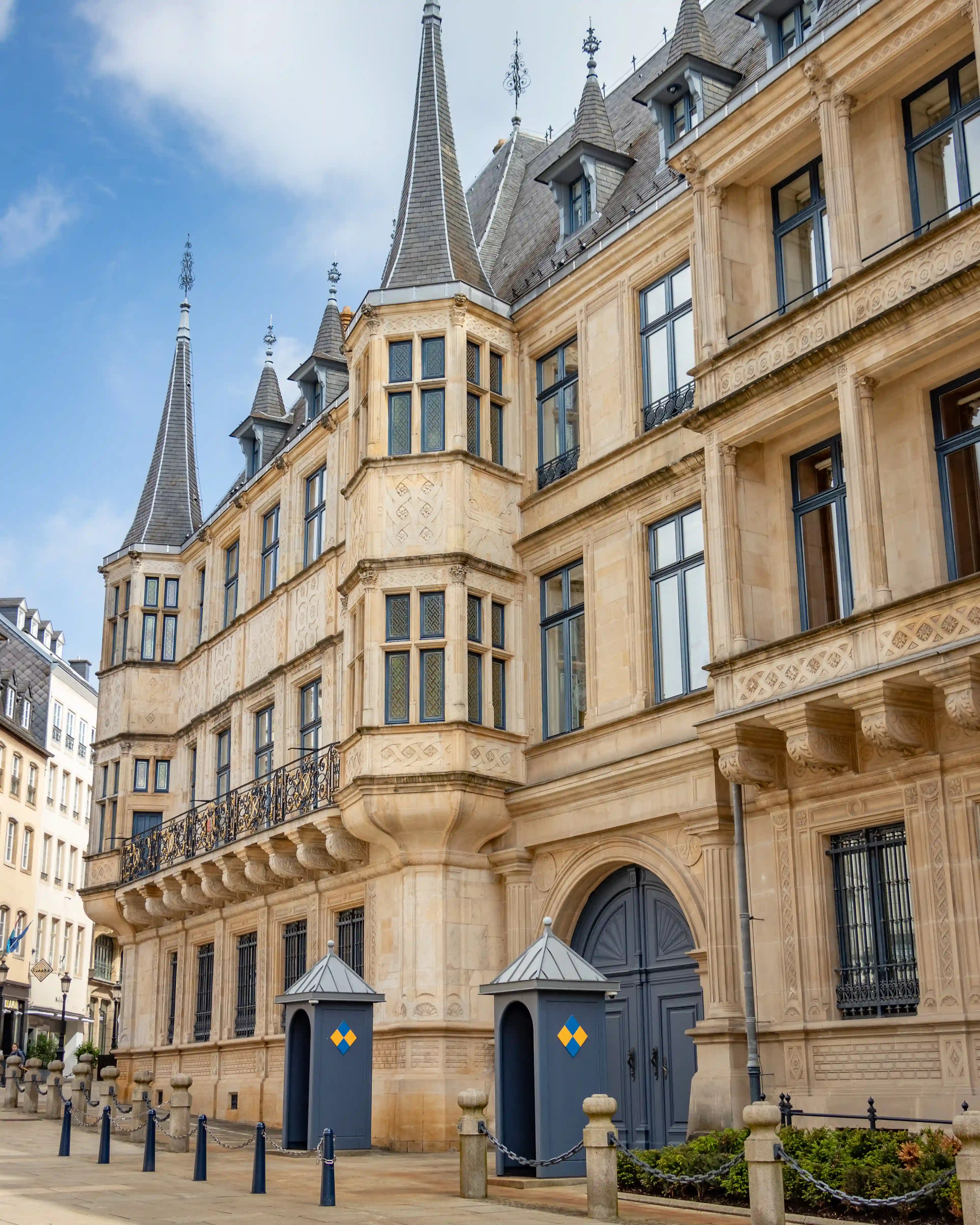 The Grand Ducal Palace in Luxembourg, with ornate stone towers, balconies, and guard booths at the entrance.