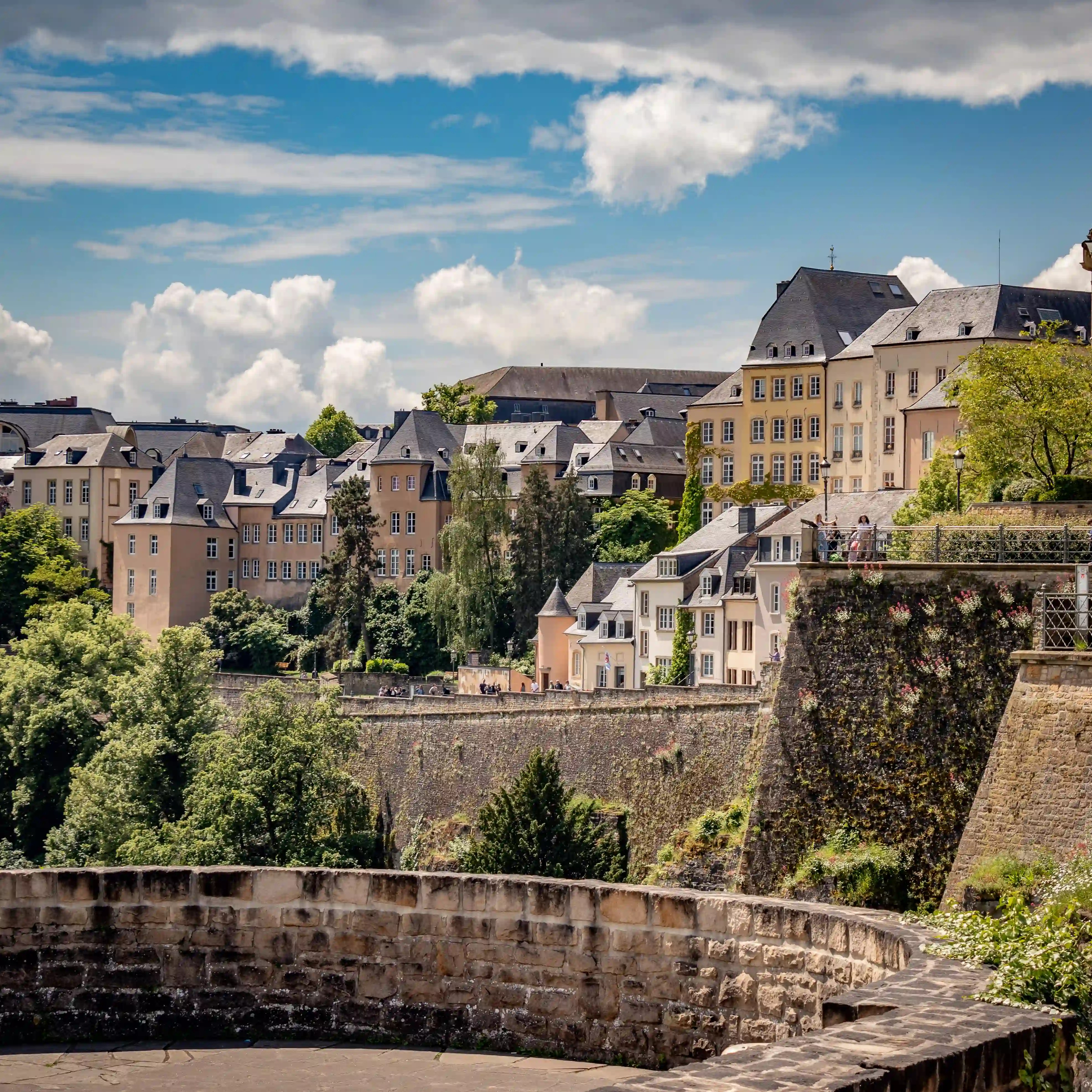 Cluster of pastel-colored houses perched on the old city walls of Luxembourg City.