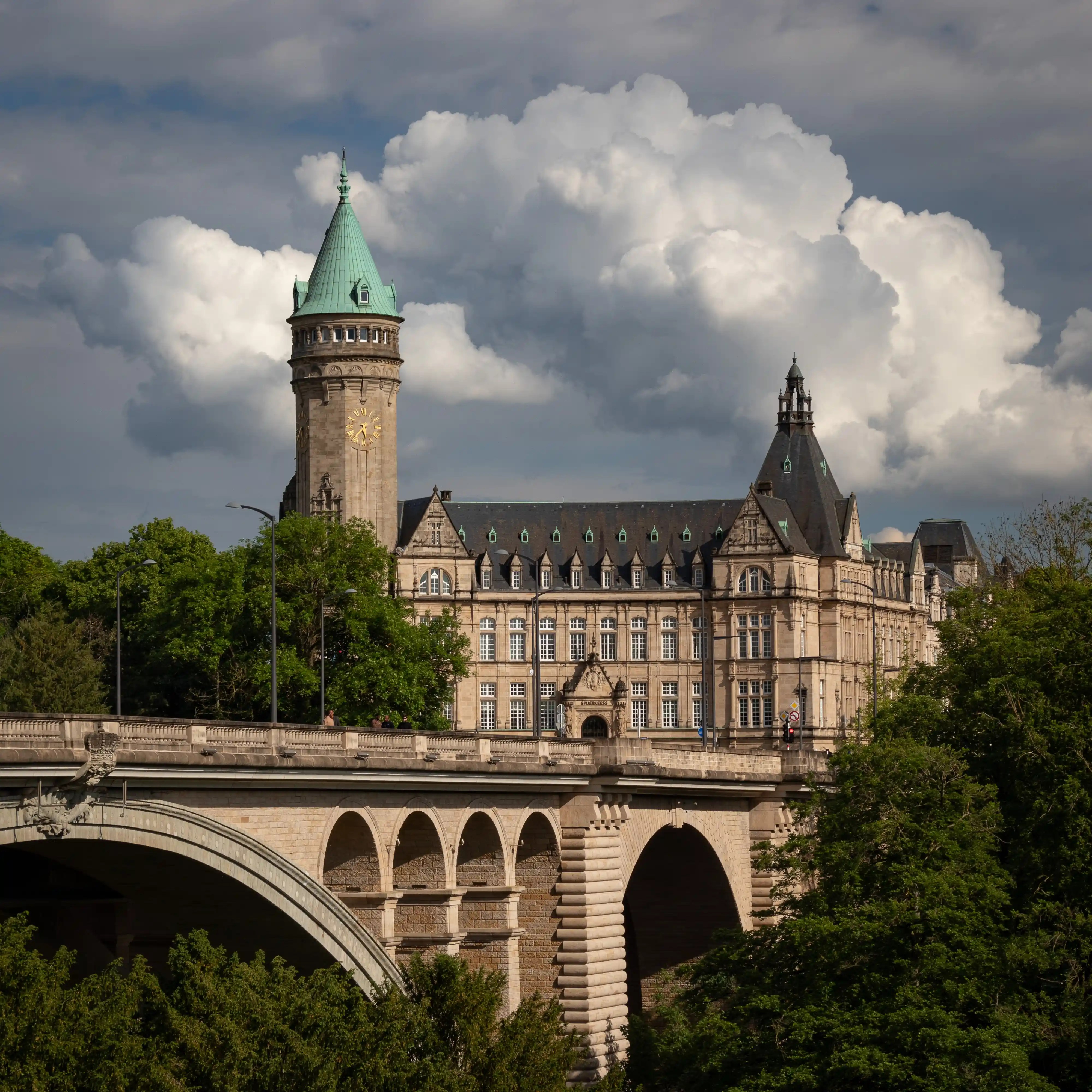 View of Adolphe Bridge with arched supports and the iconic clock tower of the Luxembourg City bank.