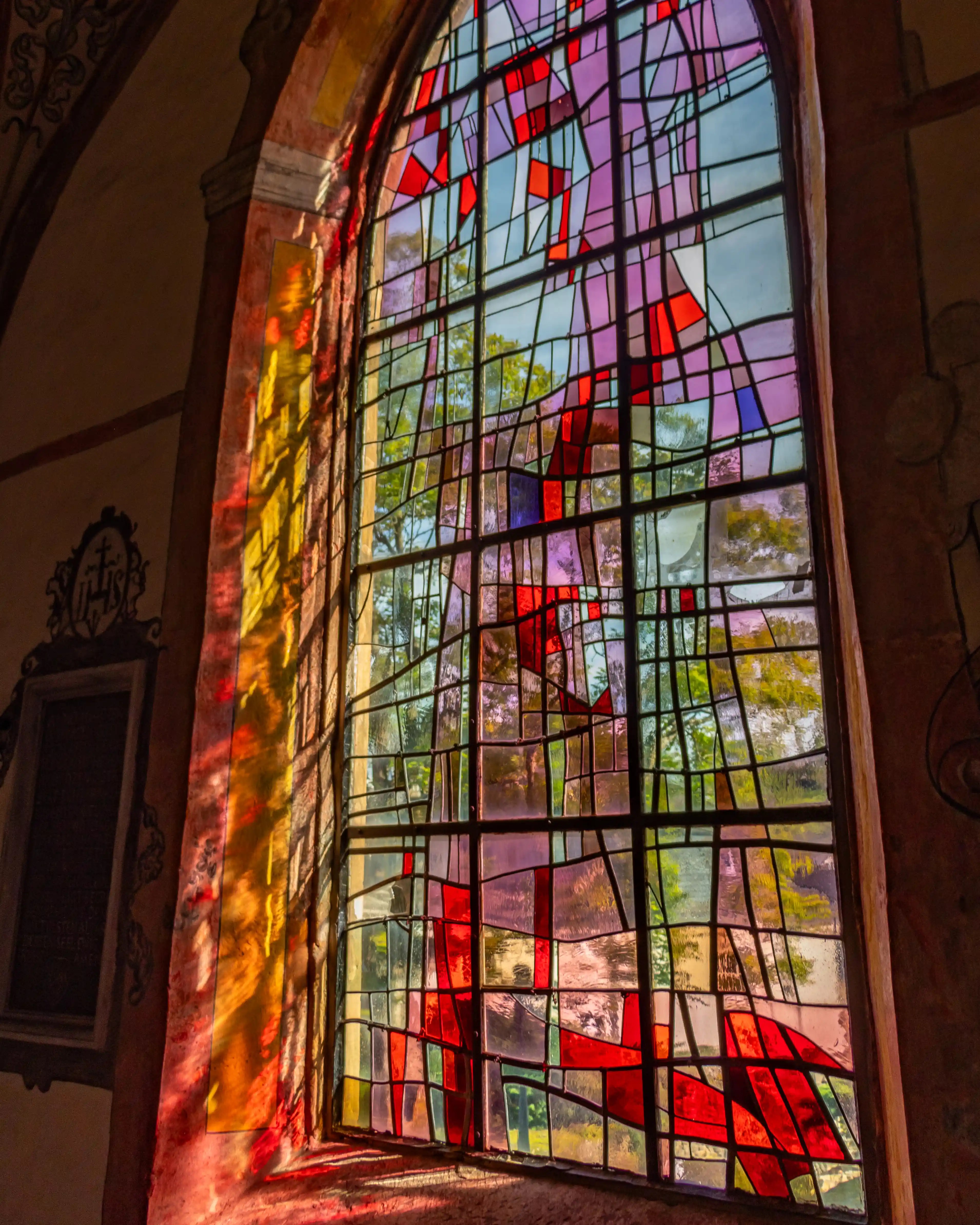 Stained glass window in the Church of Saints Peter and Paul casting colorful light patterns on the wall.