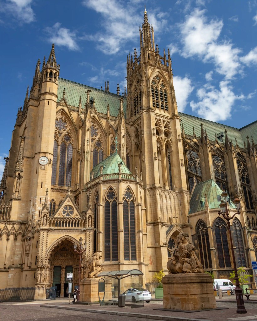 Exterior of Metz Cathedral, a Gothic church with spires and ornate details, under a blue sky.