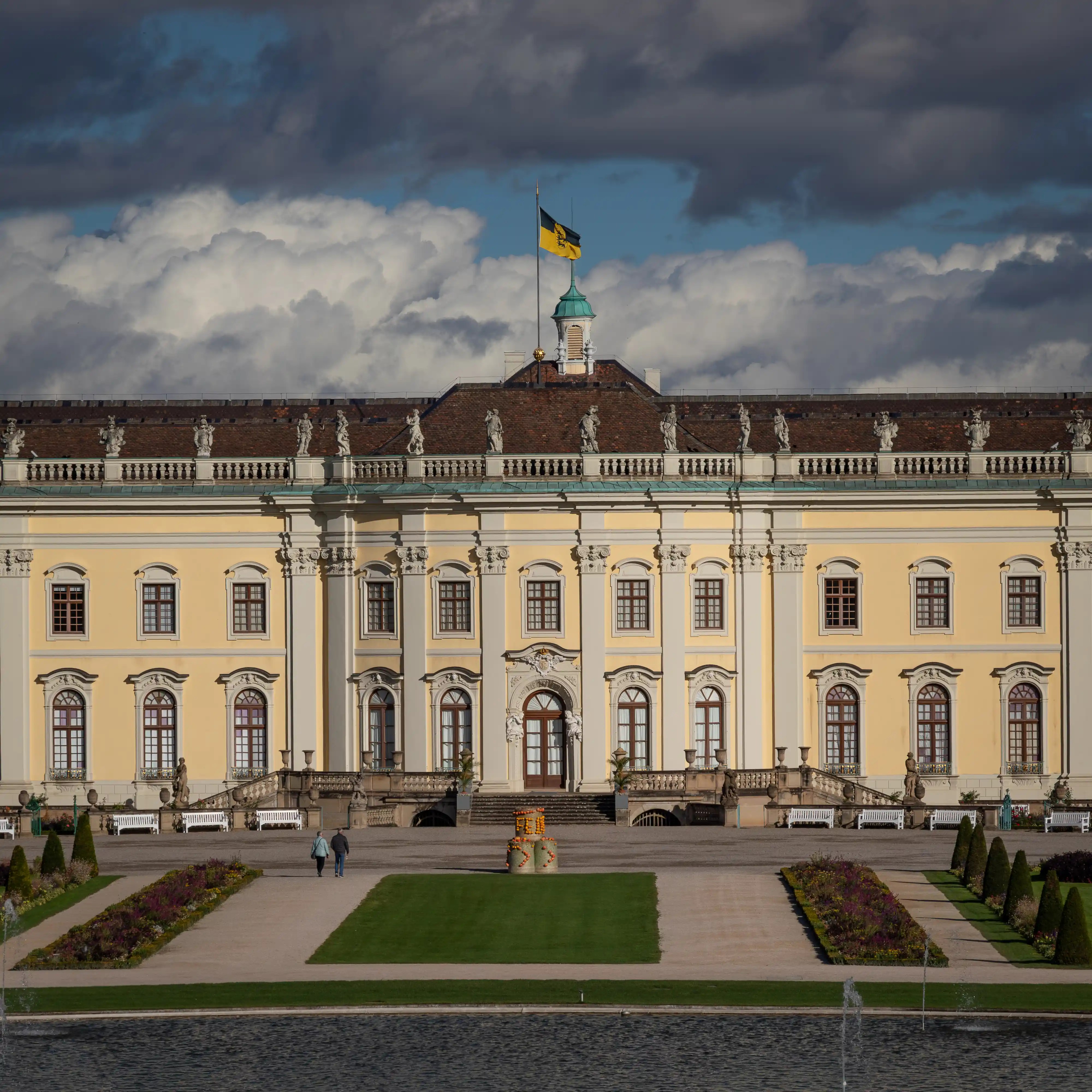 Front view of Ludwigsburg Palace in Germany with cloudy skies and gardens in front.