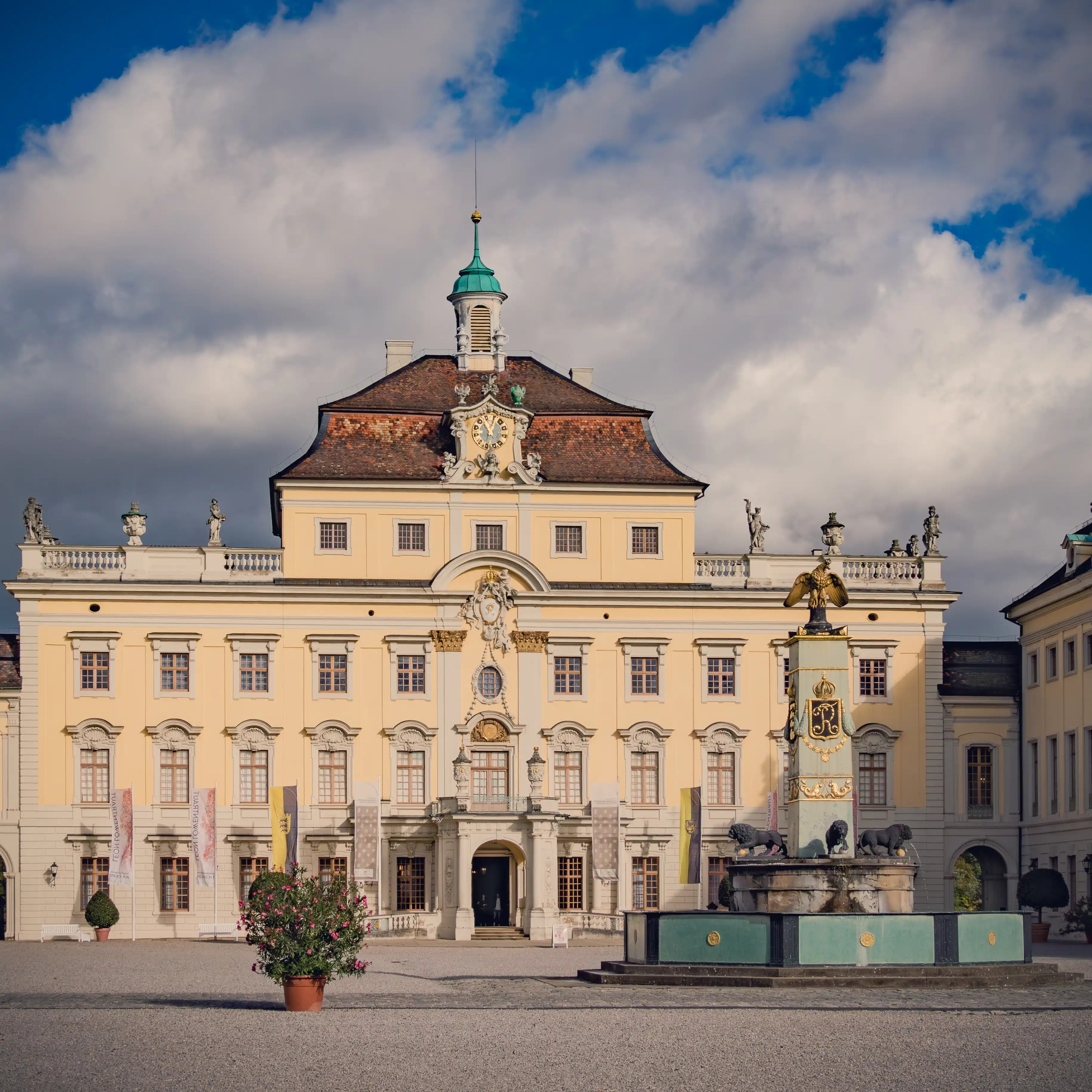Front courtyard of Ludwigsburg Palace with fountain and ornate architecture.