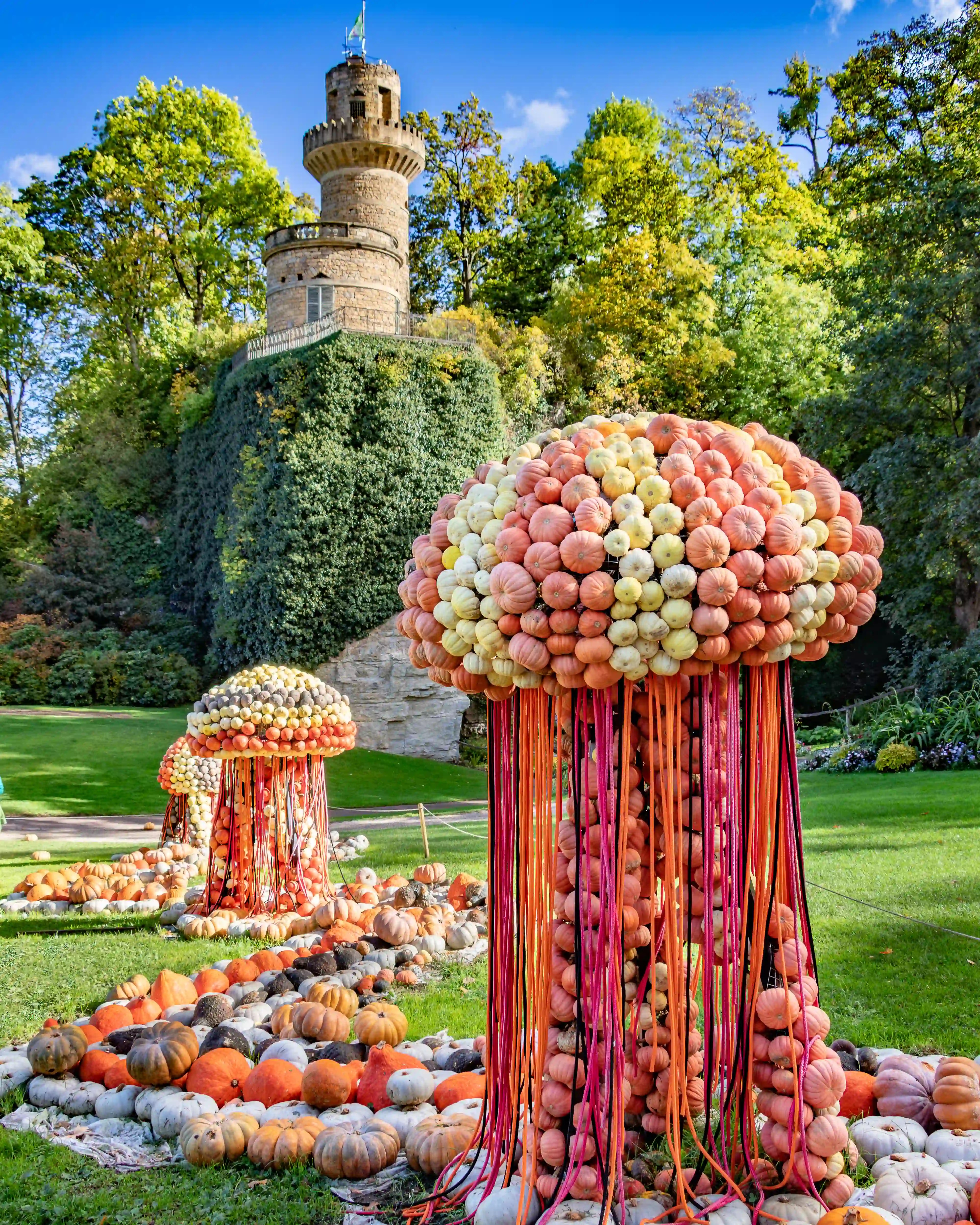 Large pumpkin jellyfish sculptures with colorful streamers in front of the Emichsburg tower.