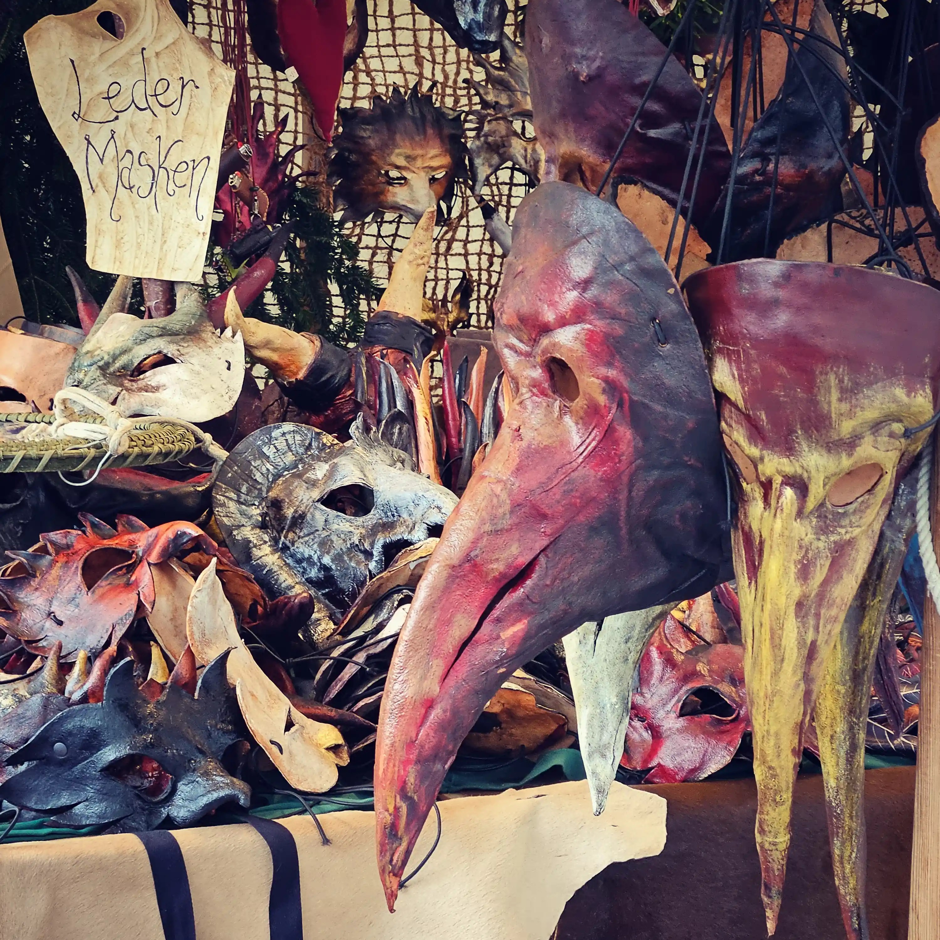A display of handmade leather masks with long beaks and fantasy designs at the Esslingen Medieval Christmas Market.