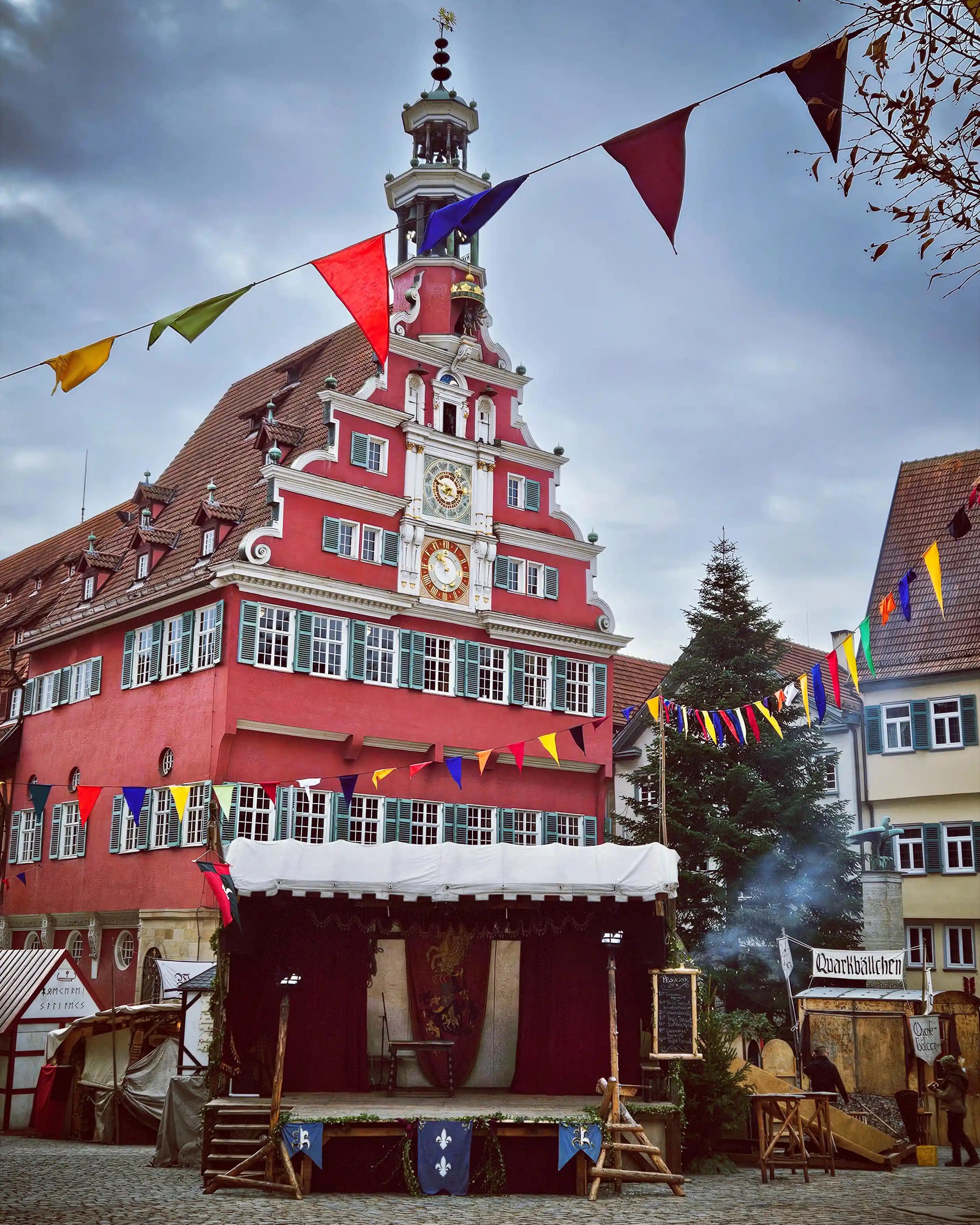 The red historic town hall of Esslingen decorated with colorful flags above the medieval market stage.
