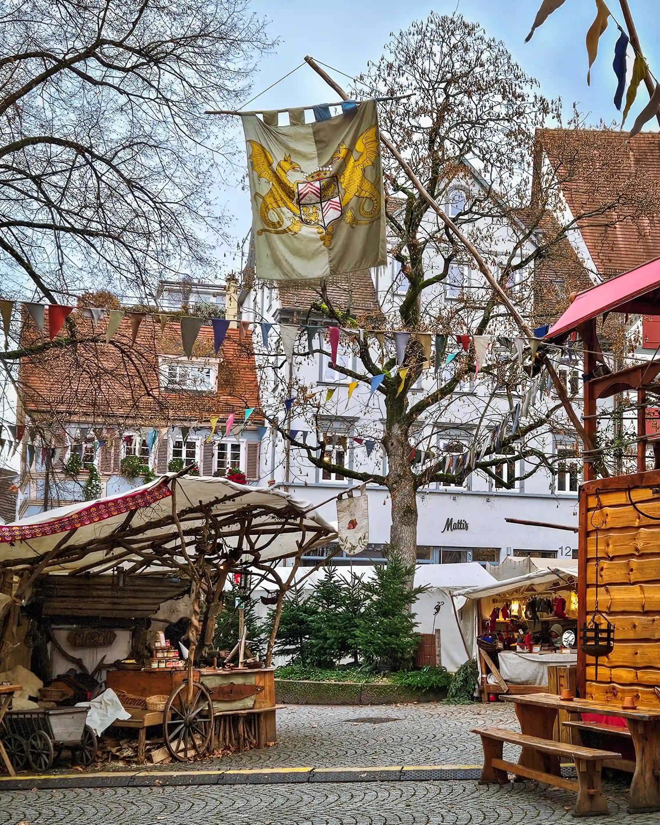 Medieval-style market stalls and banners beneath bare winter trees in Esslingen’s old town square.