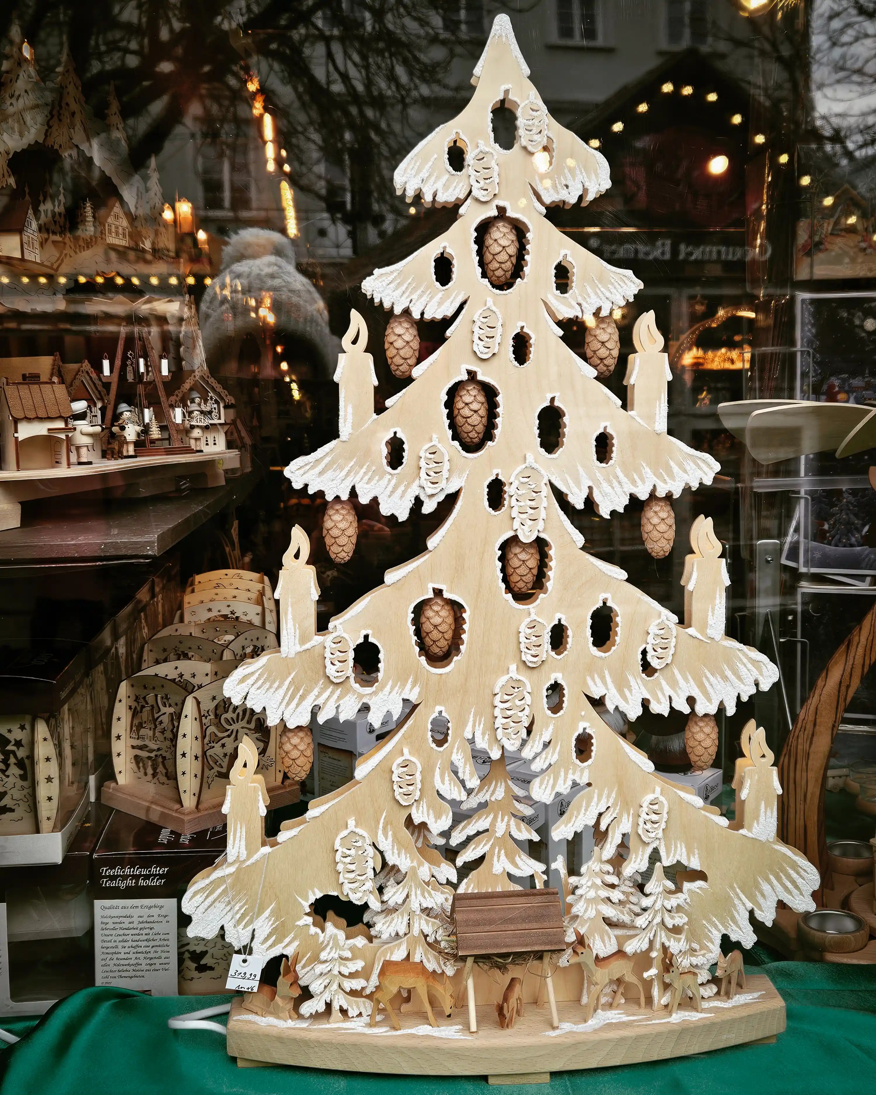 A carved wooden Christmas tree with pinecone details displayed in a shop window at the Esslingen Christmas Market.