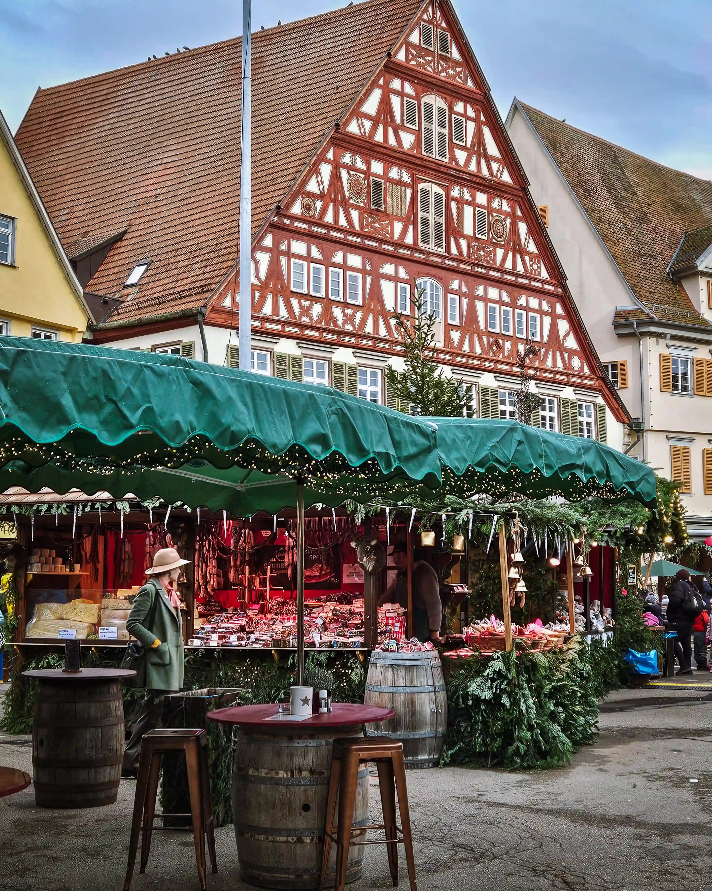 A Christmas market stall selling cheeses and meats set before Esslingen’s half-timbered buildings.