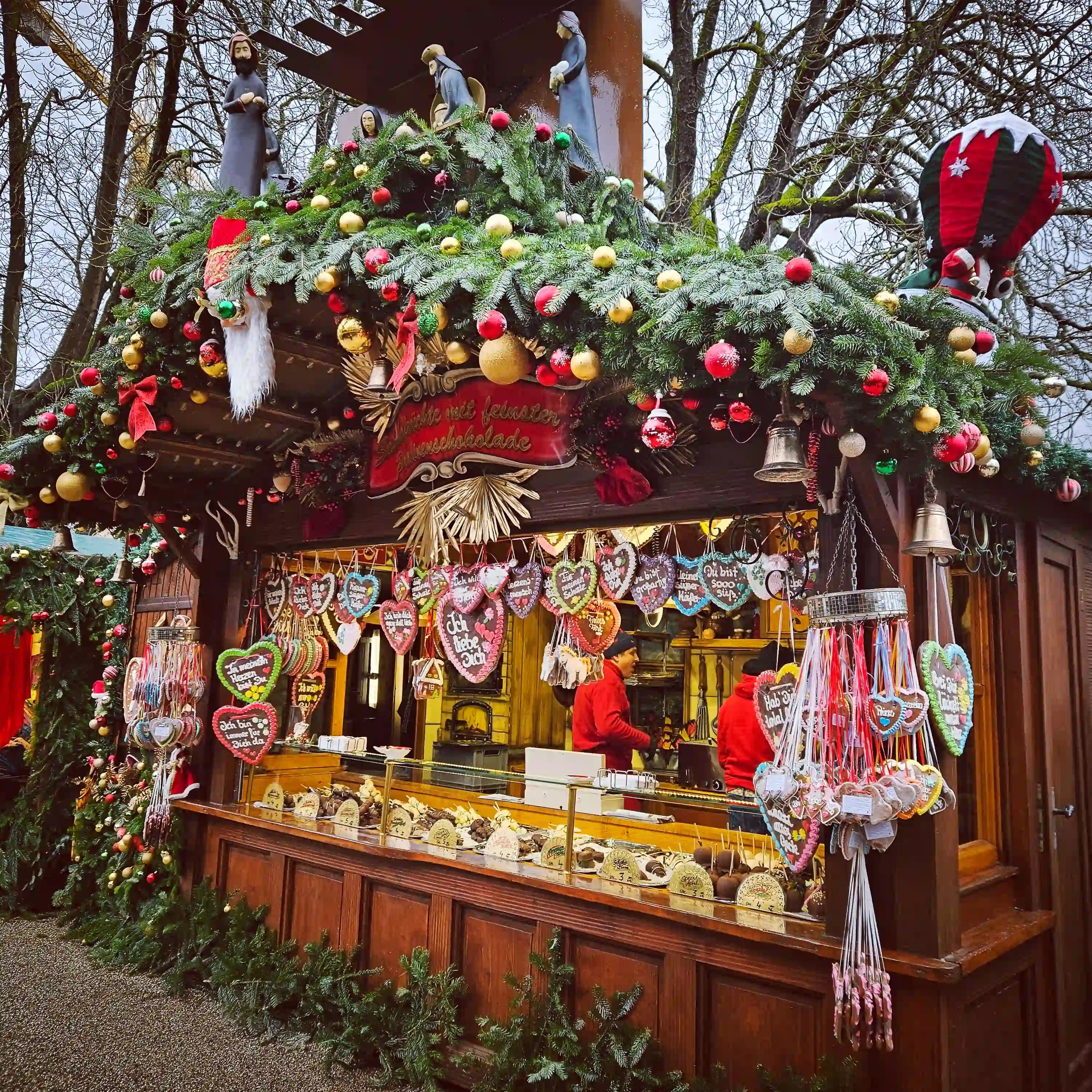 Festive wooden Christmas market stall decorated with garlands, ornaments, and gingerbread hearts in Baden-Baden.