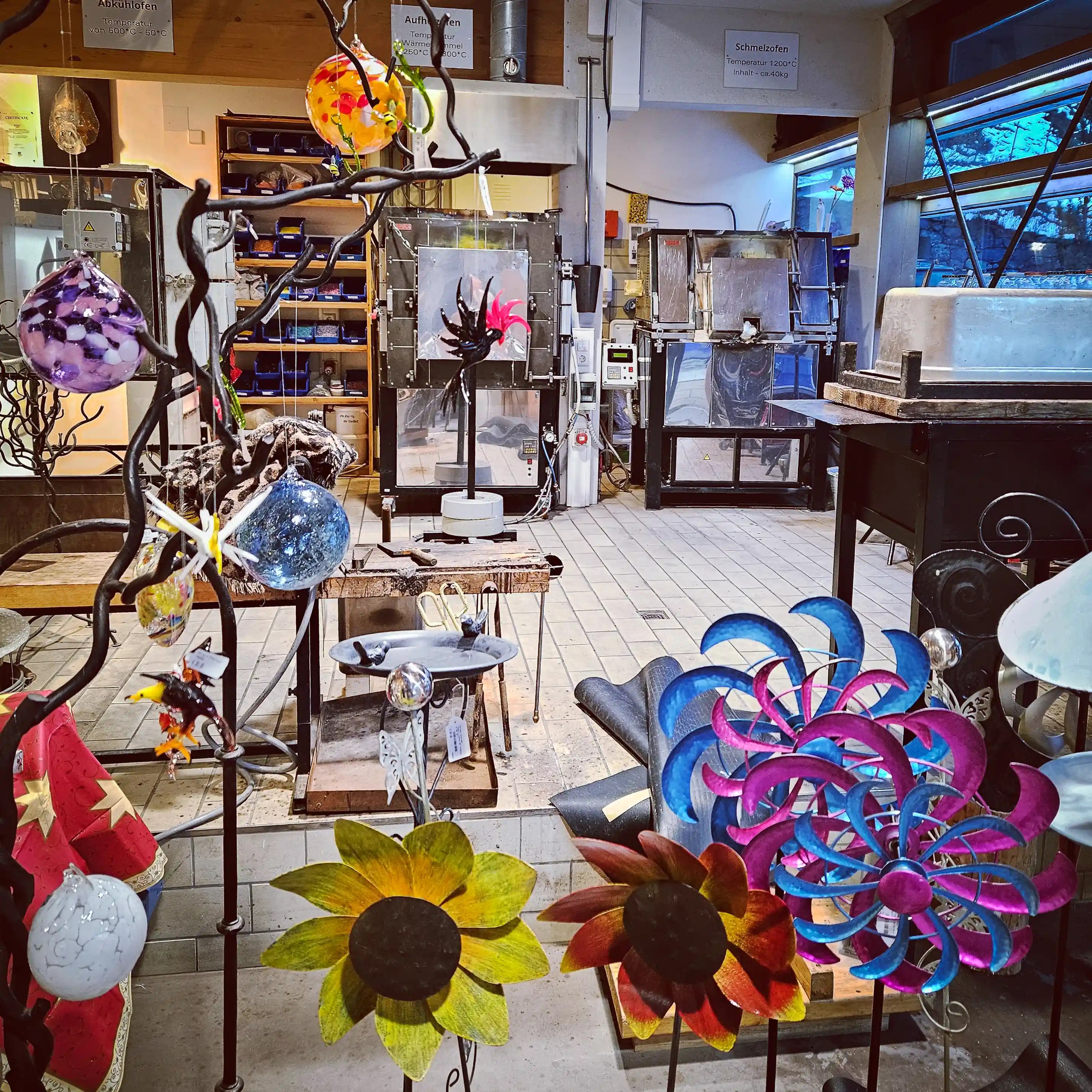 Interior of a glassblowing studio at Hofgut Sternen with colorful handmade glass ornaments and metal art.