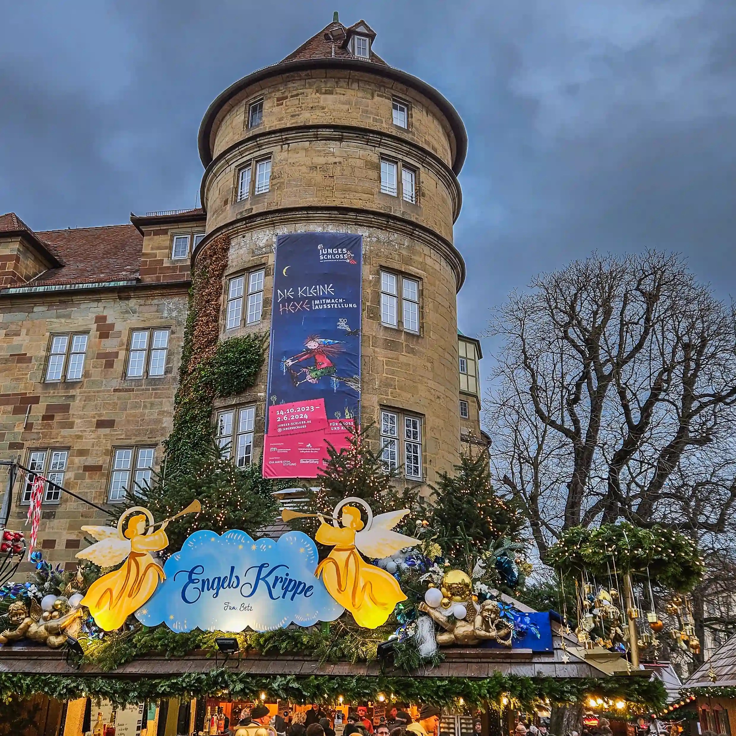 The round tower of Stuttgart’s Old Castle decorated for the holidays with an angel-themed Christmas market stall below.
