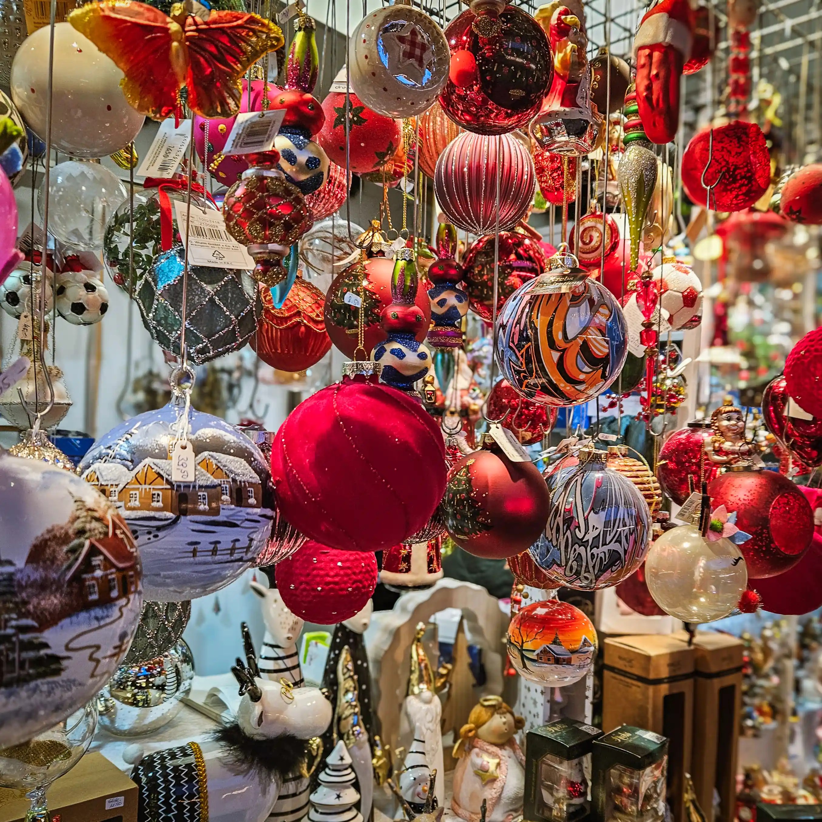 Close-up of colorful glass Christmas ornaments and decorations hanging in a market stall.