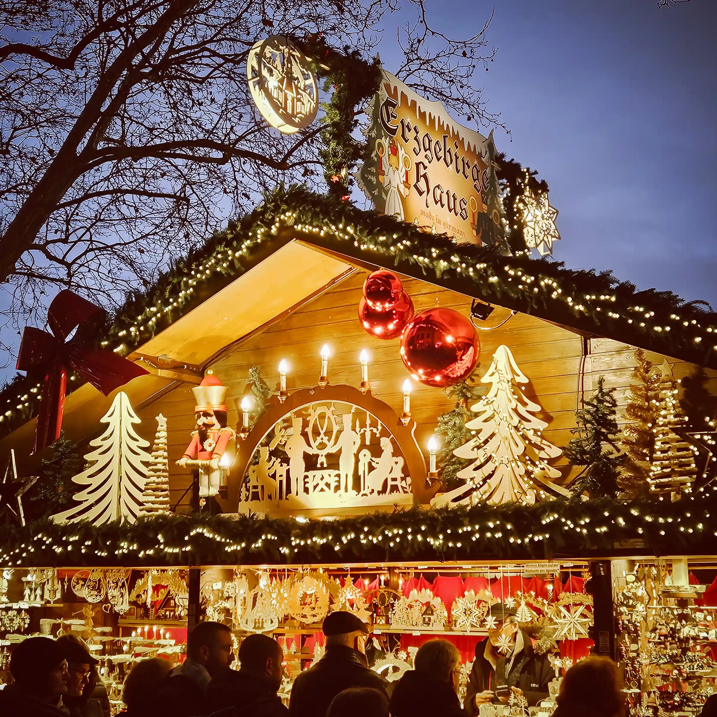 Erzgebirge-style wooden craft stall decorated with lights, nutcrackers, and Christmas schwibbogens at the Stuttgart Christmas Market.