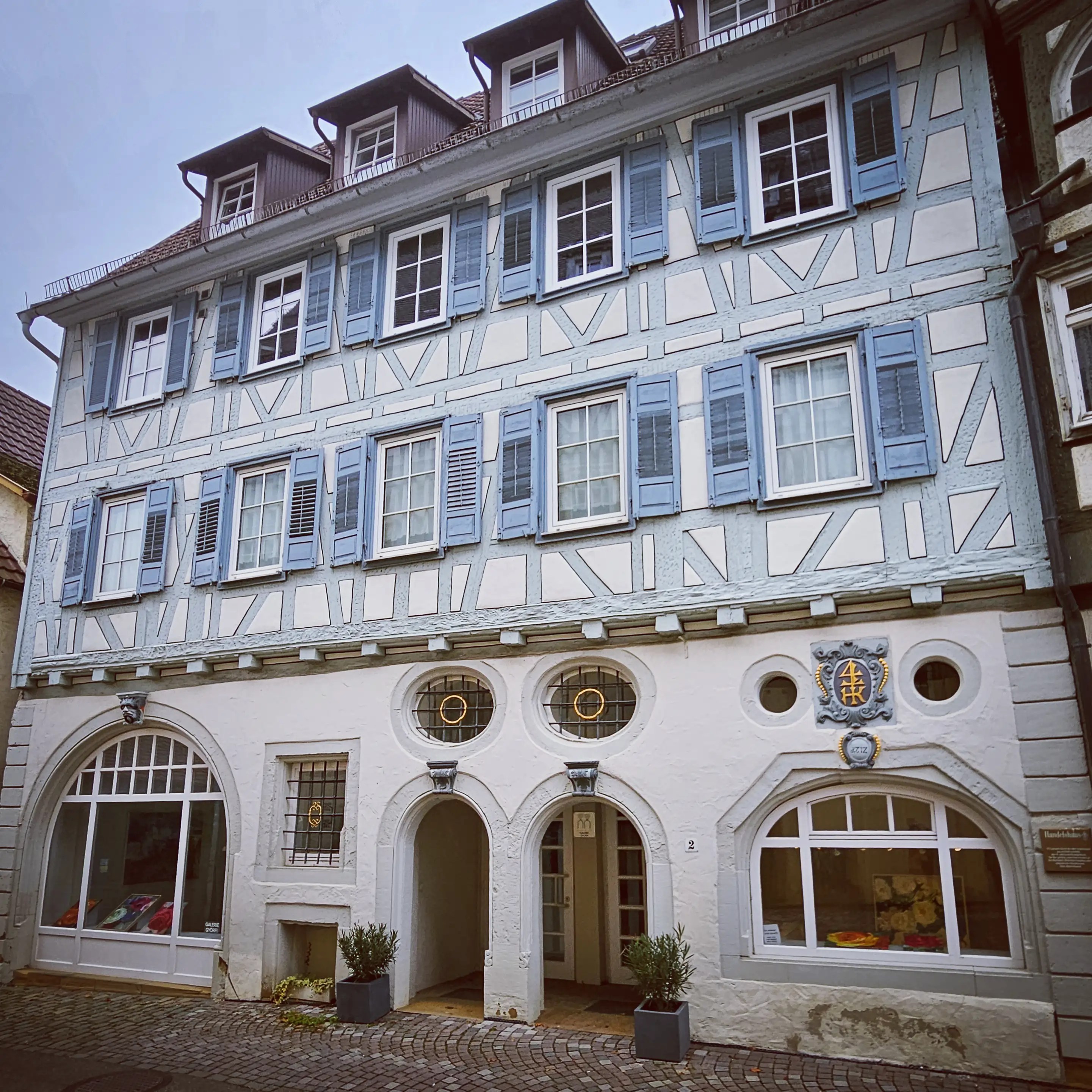 Light blue half-timbered house with circular windows and blue shutters in Herrenberg.