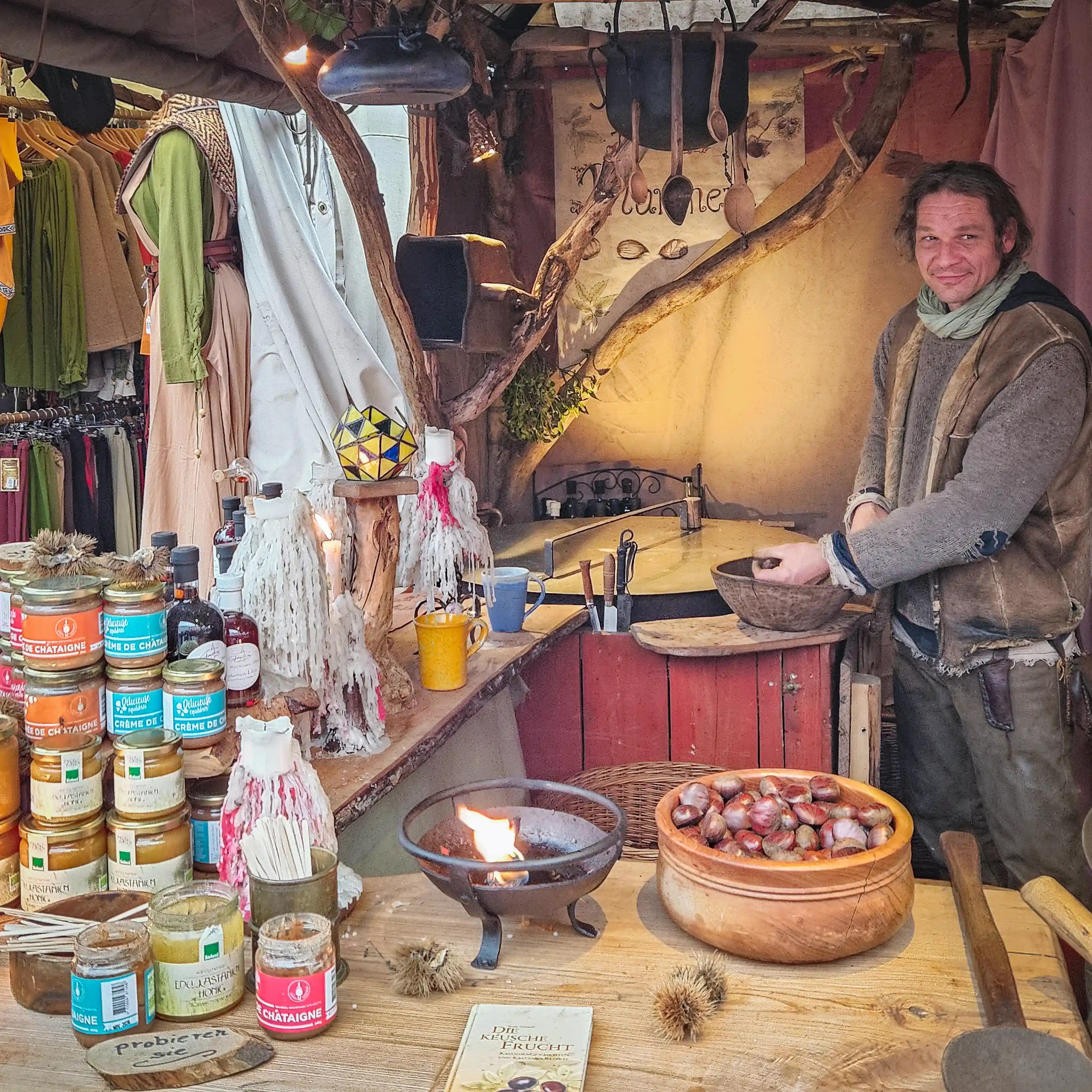 A vendor in medieval attire roasting chestnuts and selling handmade products at the Esslingen Medieval Market.
