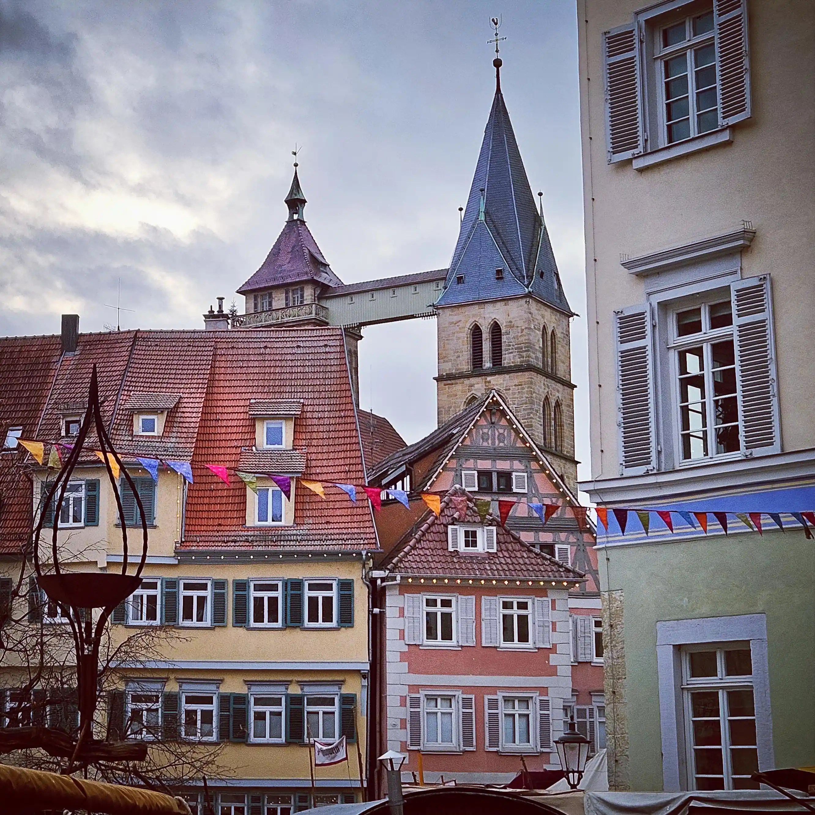 The spire of St. Dionys Church rising above pastel-colored houses and market rooftops in Esslingen.