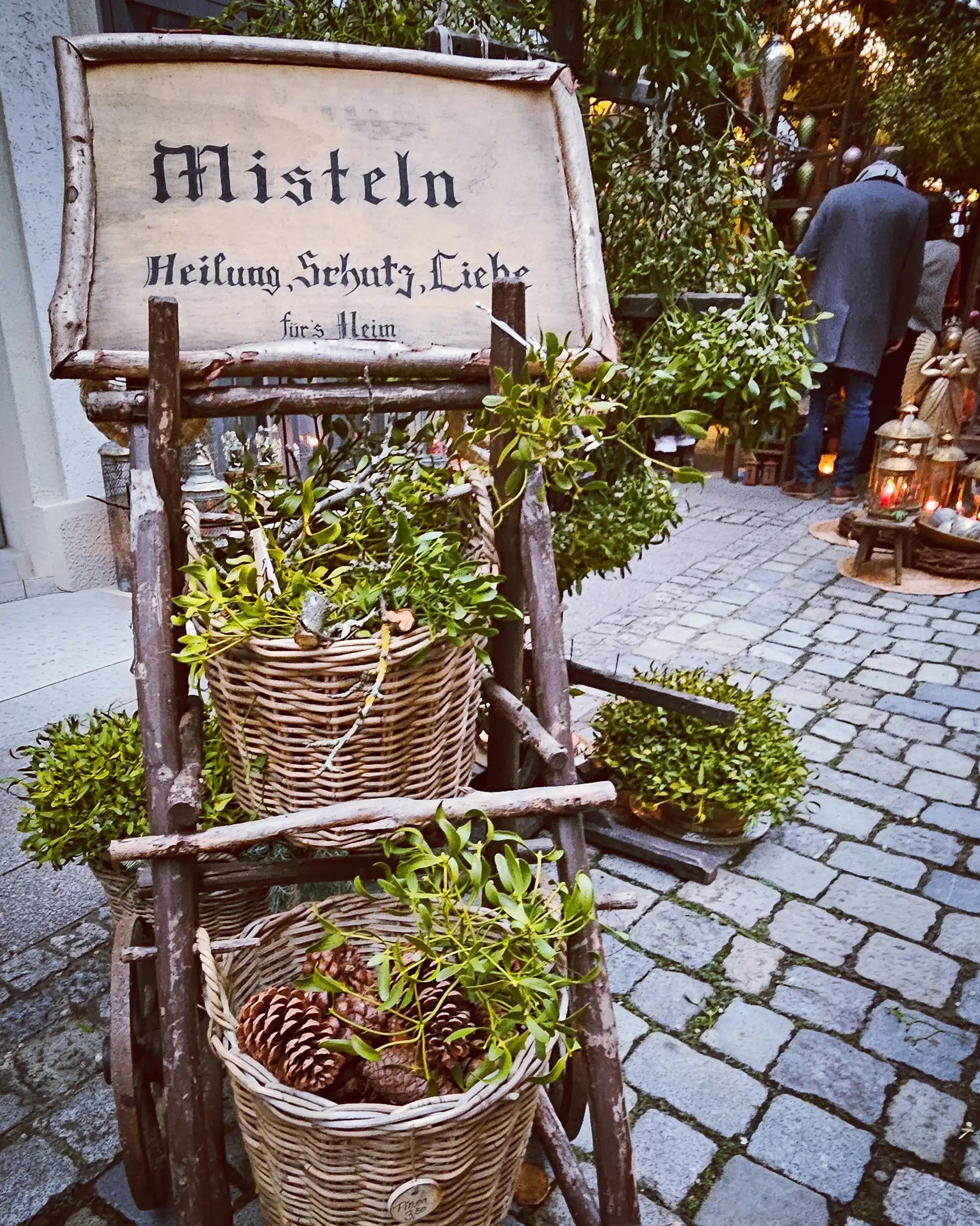 A rustic wooden cart filled with mistletoe and pinecones at the Esslingen Christmas Market.