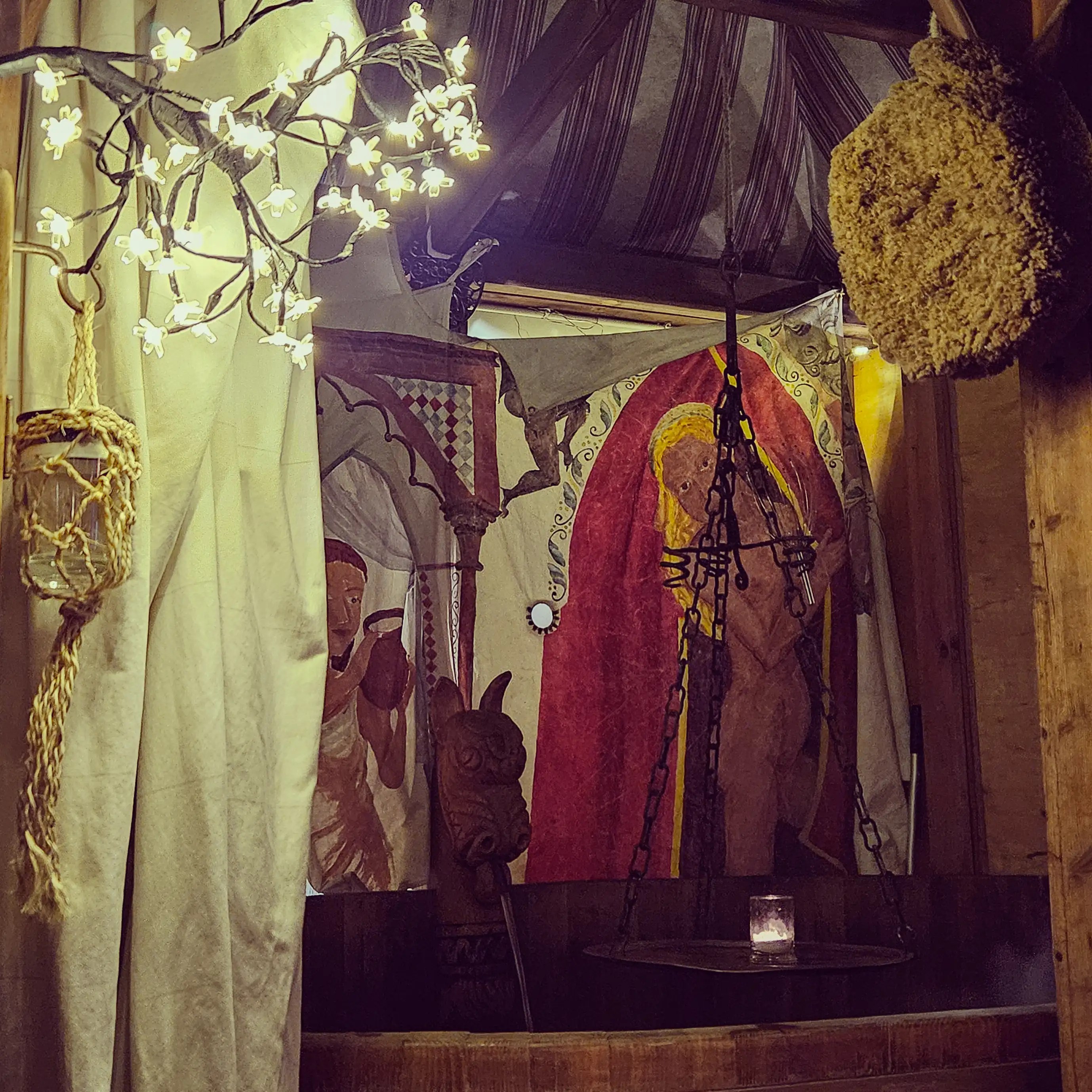 A candlelit medieval bathhouse display with painted curtains and rustic wooden details at the Esslingen Market.