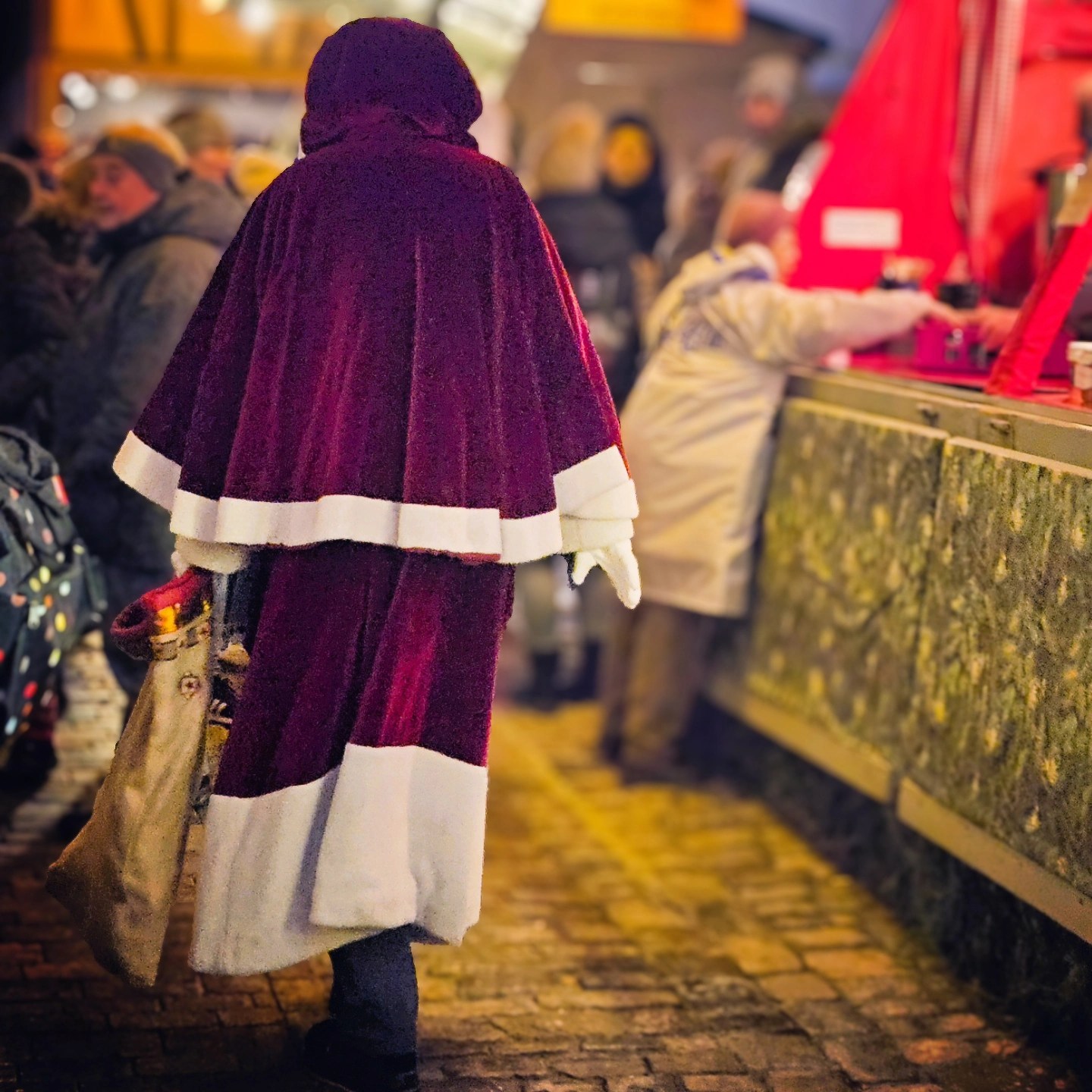 Person in a deep red Santa-style cloak walking through the Rothenburg Christmas Market.