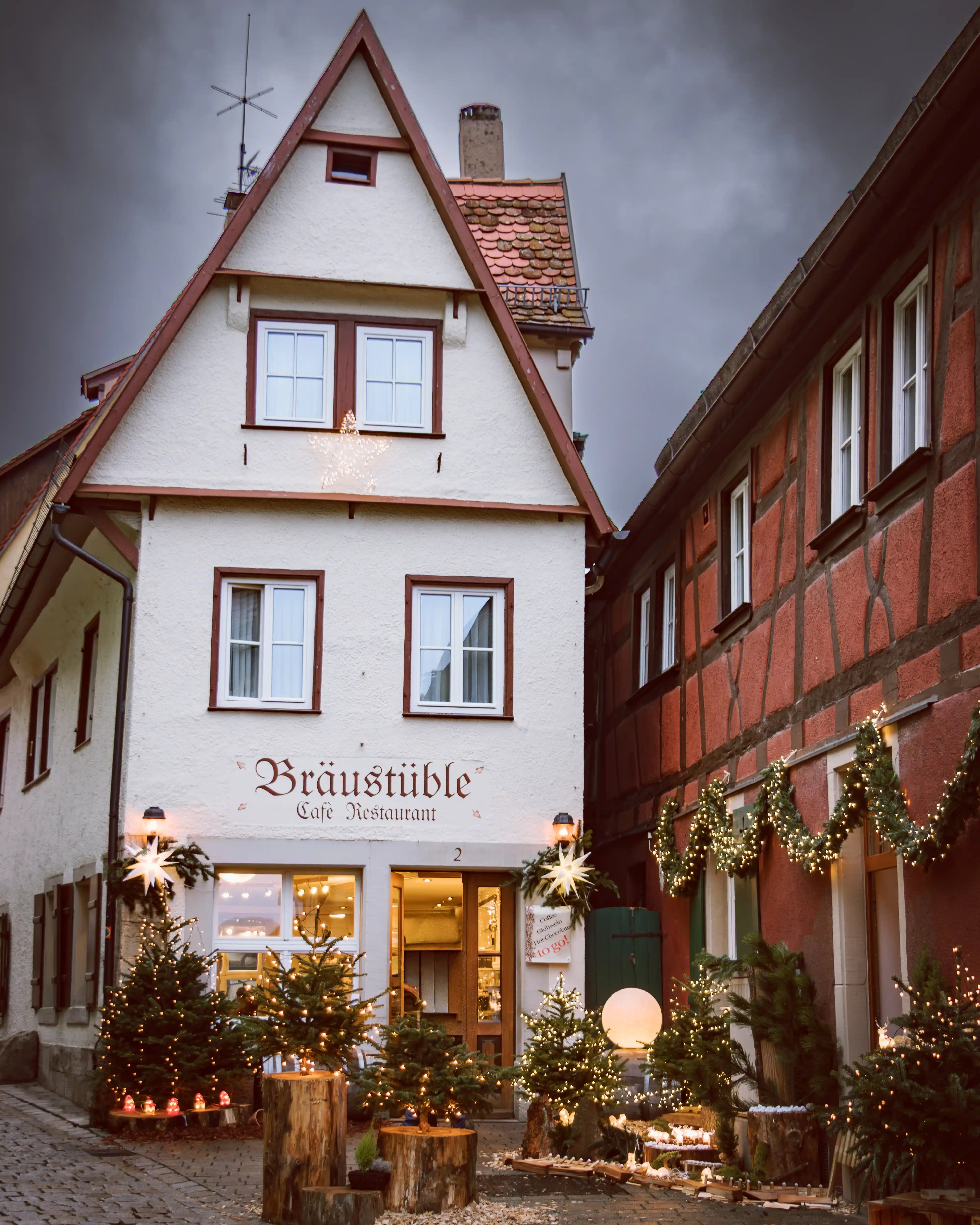 Bräustüble Café in Rothenburg ob der Tauber decorated with twinkling Christmas trees and garlands.