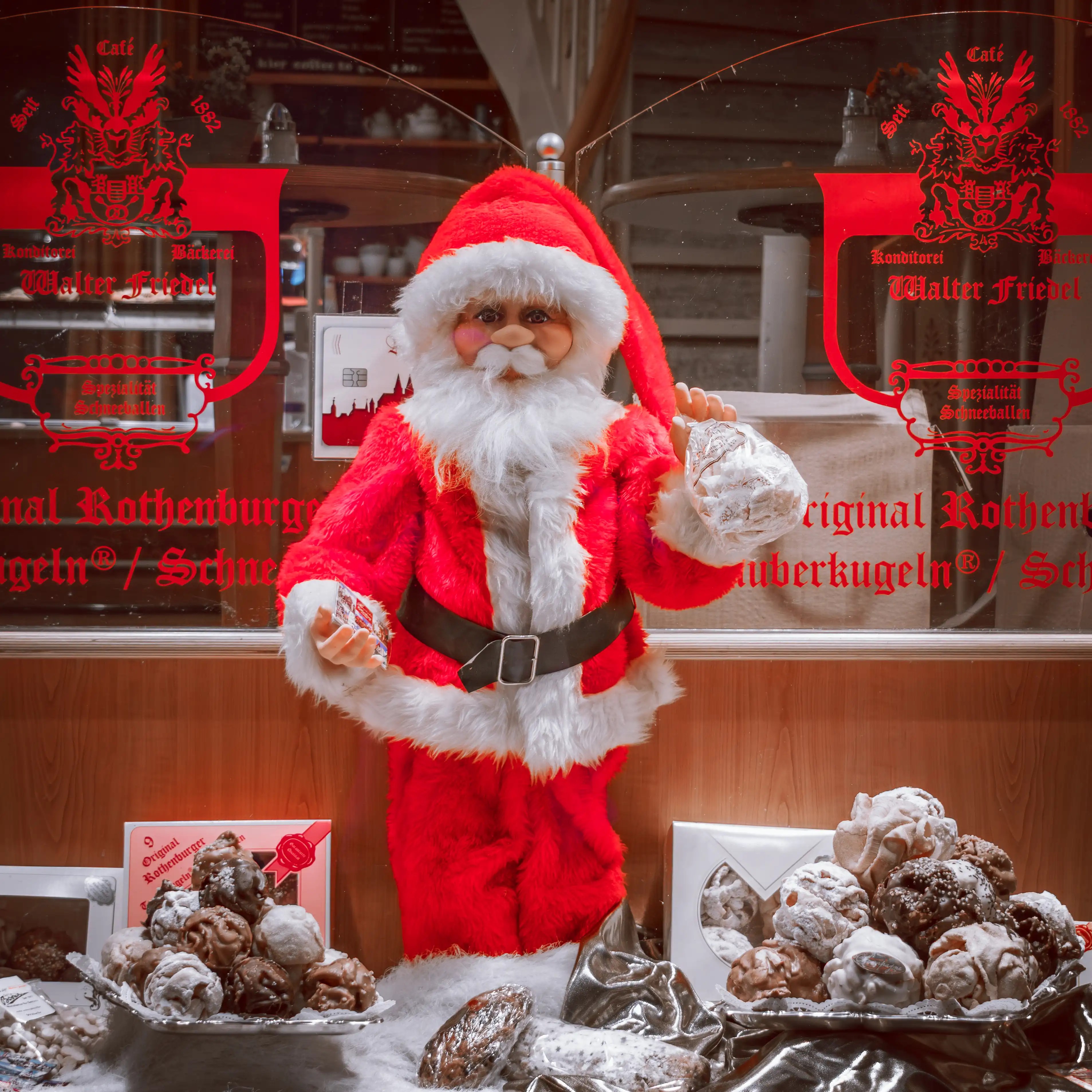 Santa figure in a bakery window holding a Schneeballen pastry at Walter Friedel Café in Rothenburg ob der Tauber.