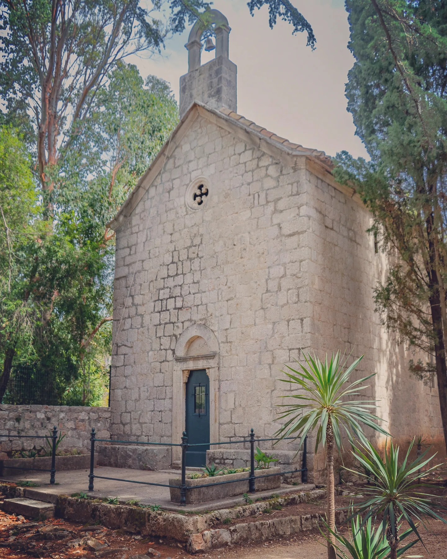 Small stone Chape of the Annunciation on Lokrum Island surrounded by trees and plants.
