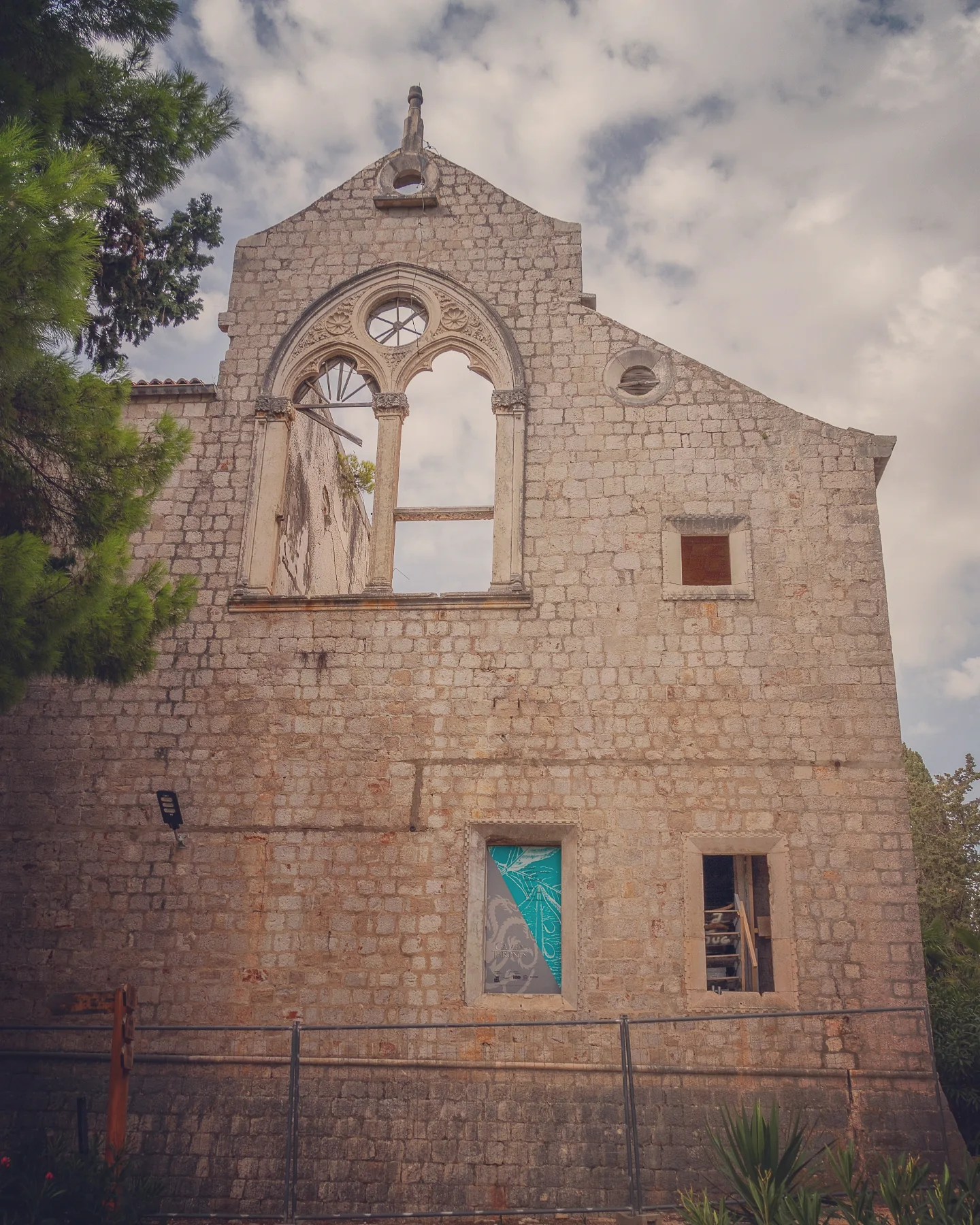 Stone façade of the ruined Benedictine Monastery on Lokrum Island with Gothic-style windows.