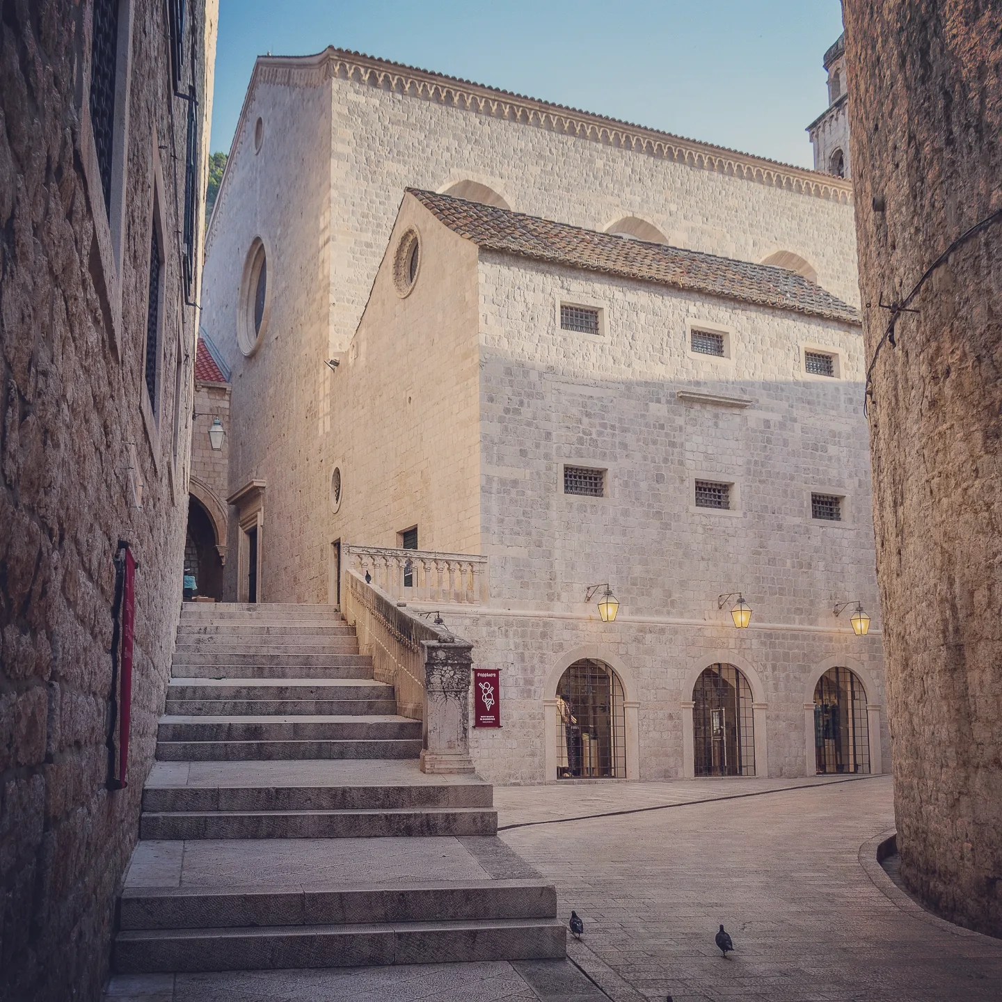 Dominican Monastery in Dubrovnik’s Old Town with stairway and arched windows.